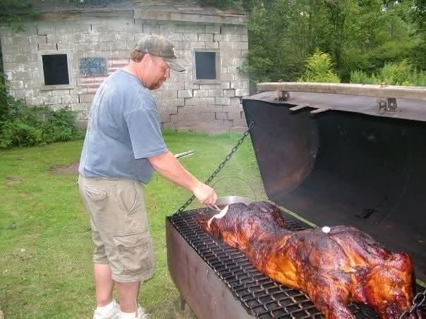 A man cooking a pig on a grill