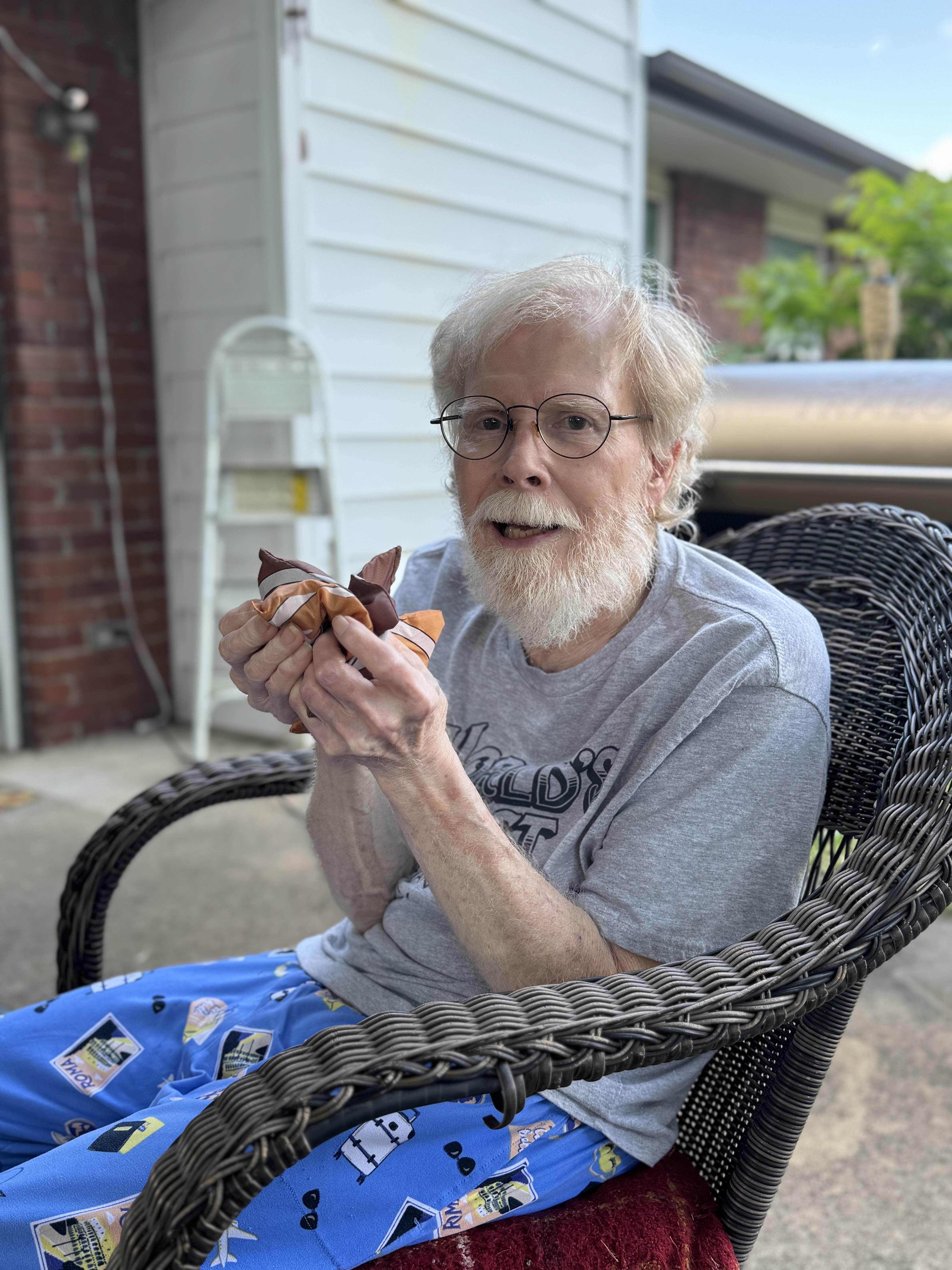 A man sitting in a wicker chair eating food