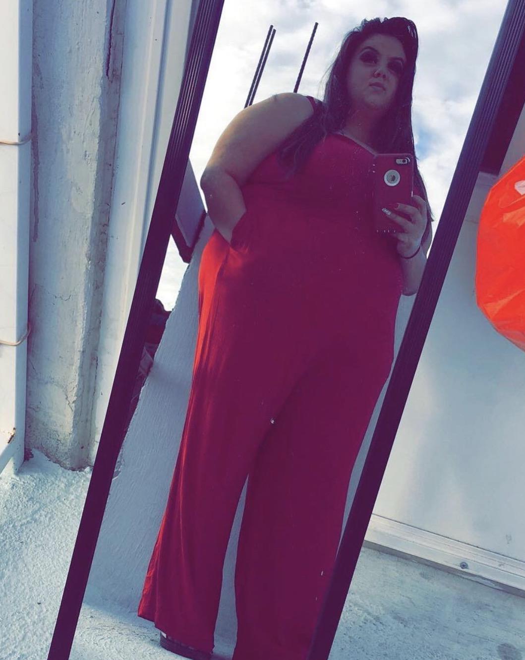 A woman in a red jumpsuit taking a selfie