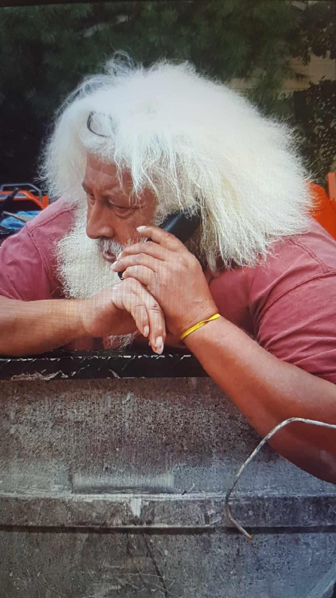A man with white hair talking on a cell phone