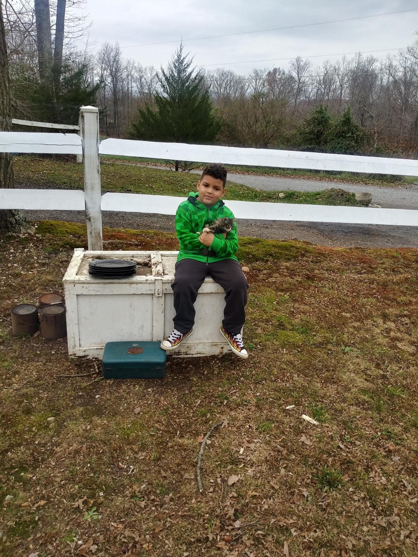 A boy sitting on a chest outside