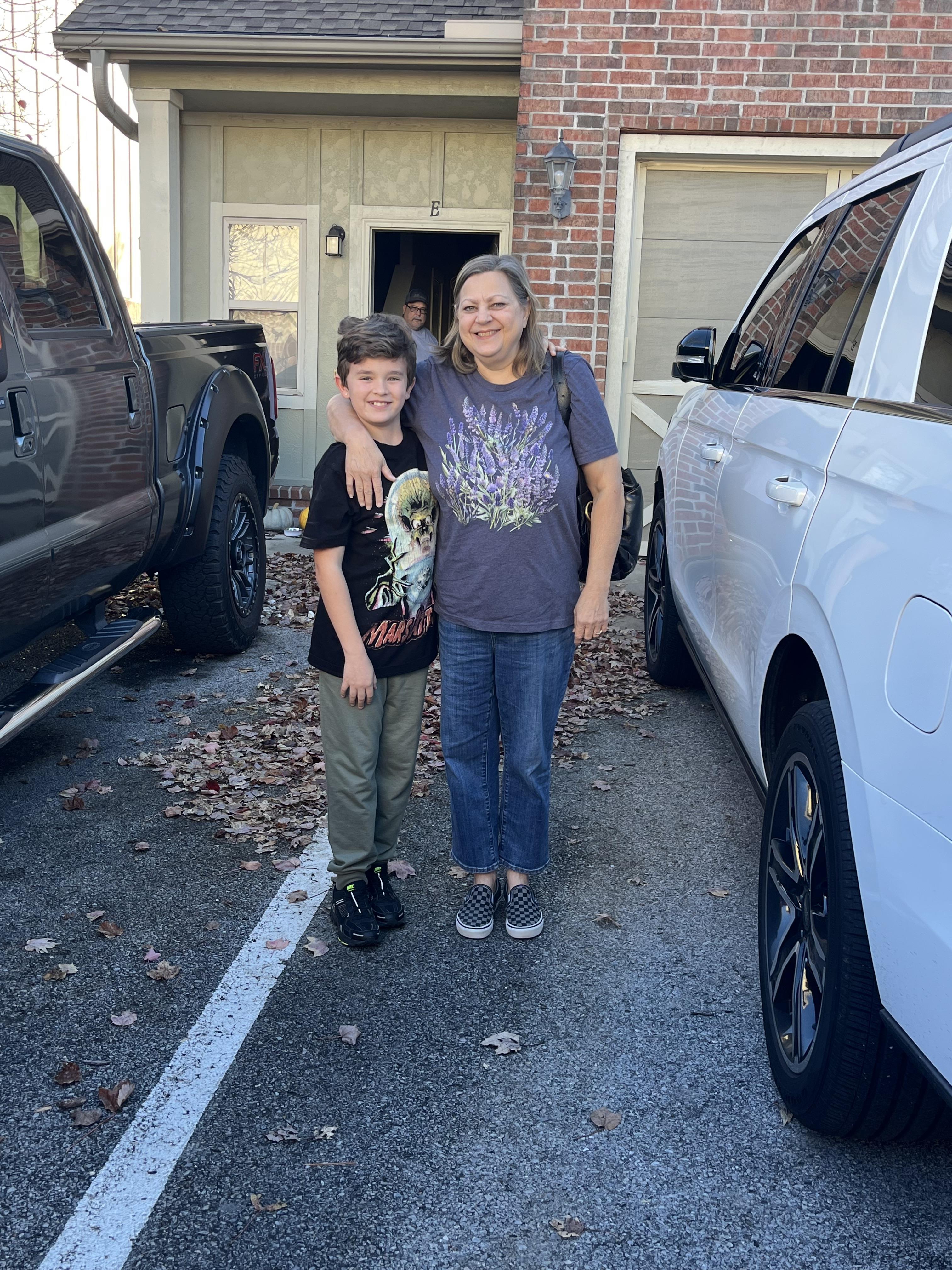 A woman and boy standing in front of a car