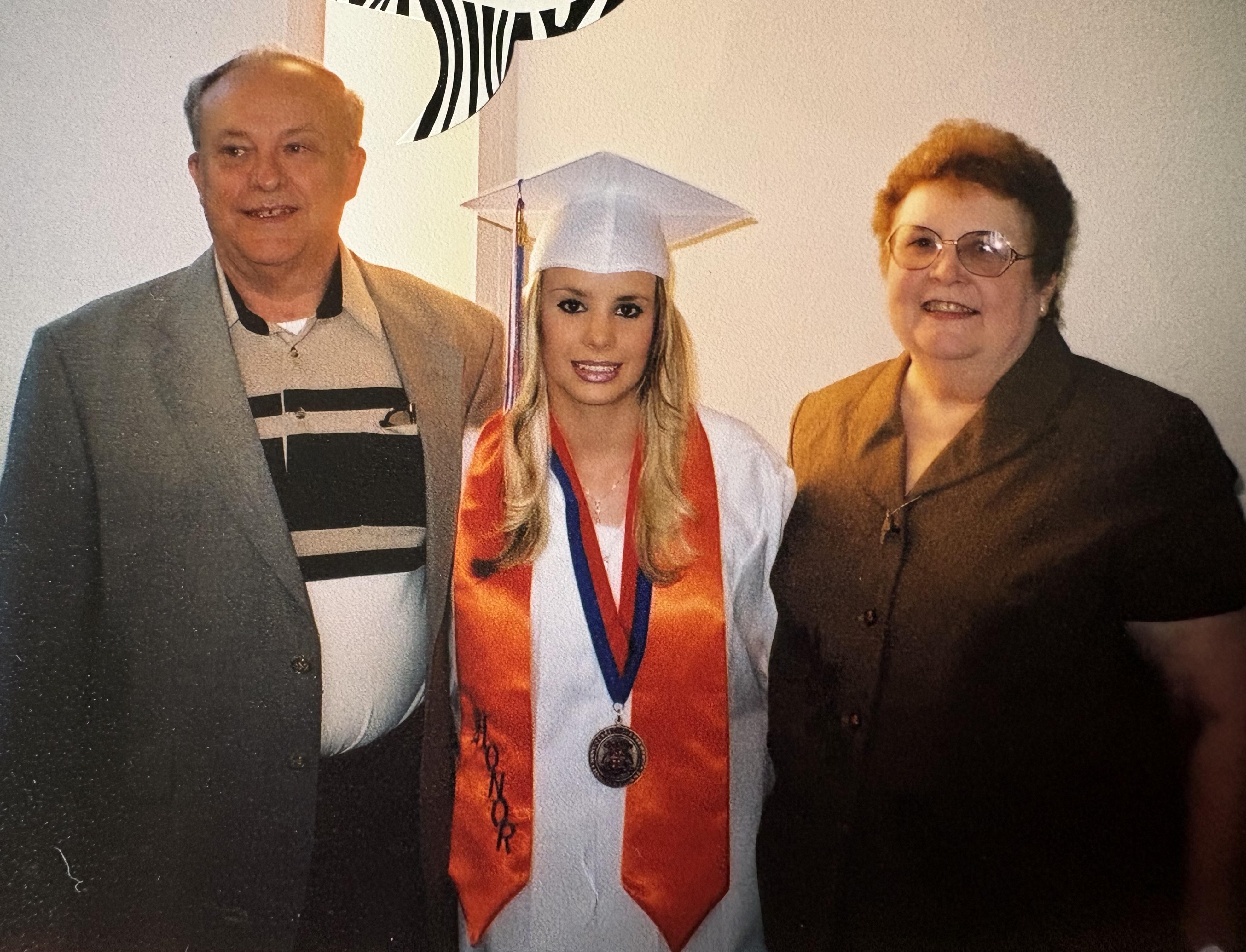 A woman in a cap and gown with a man and woman in a room