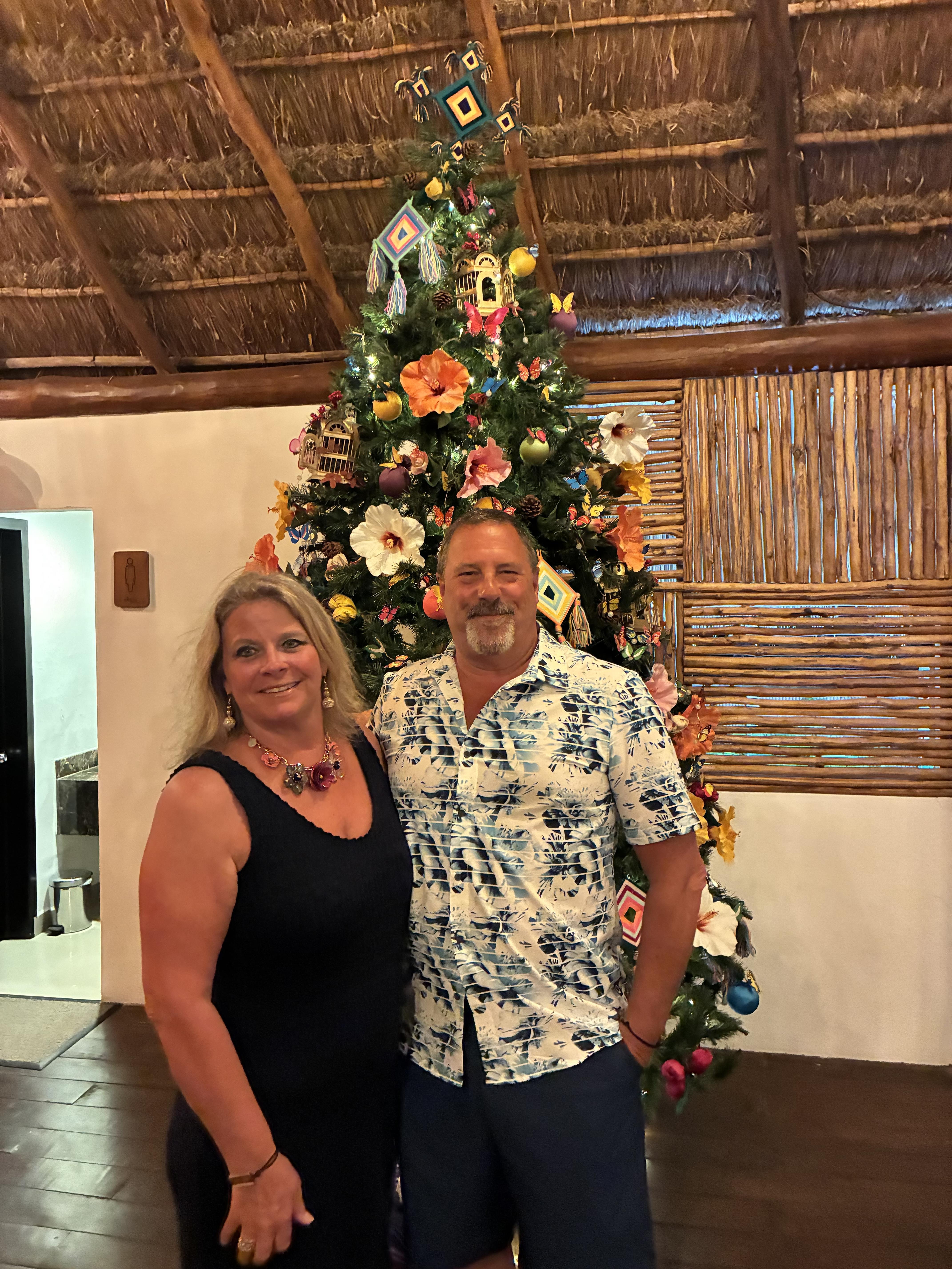 A man and woman standing in front of a christmas tree