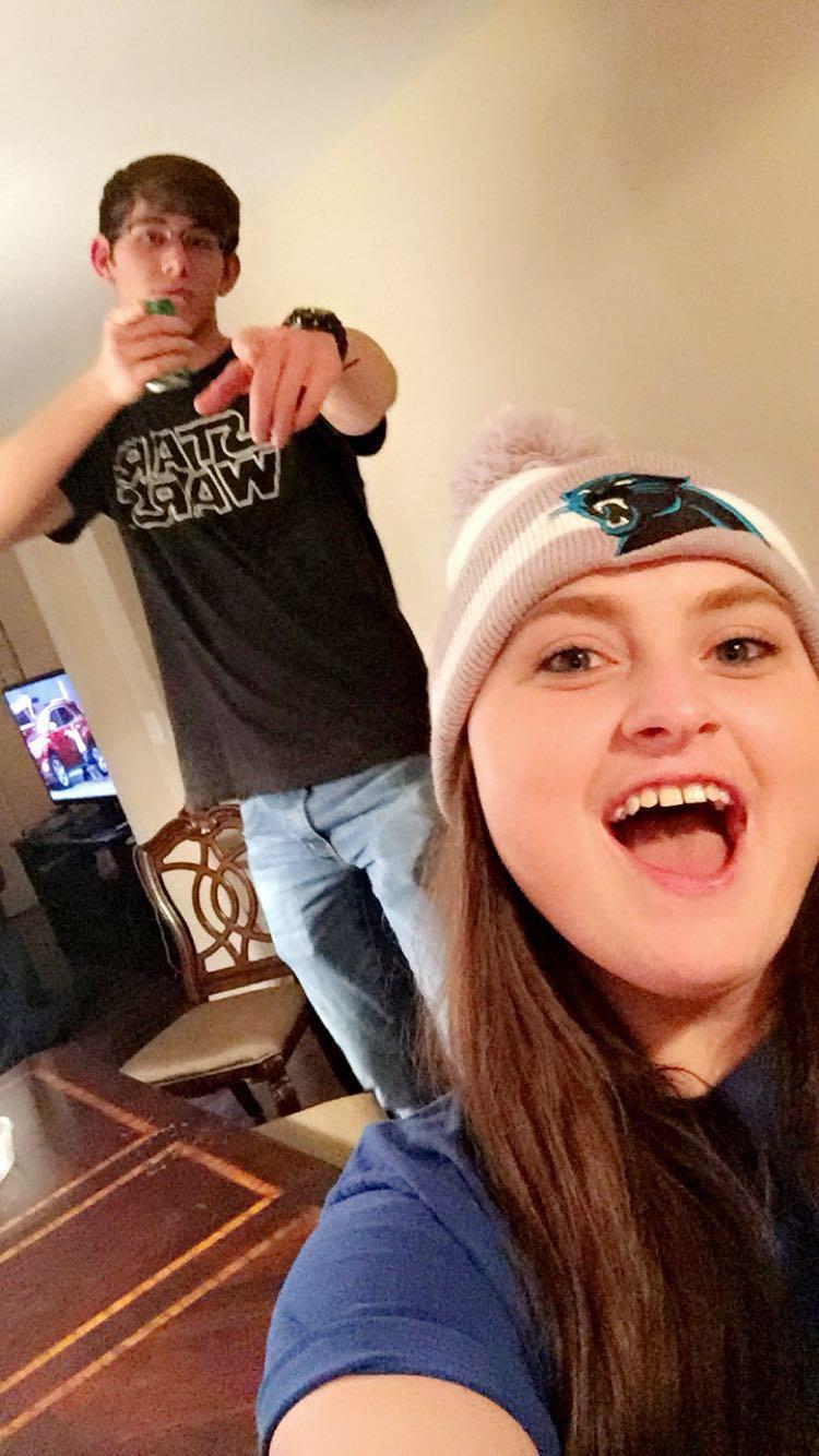 A woman taking a selfie with a man behind her