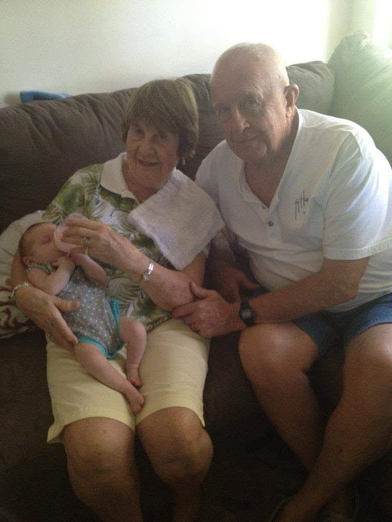 A man and woman sitting on a couch with a baby