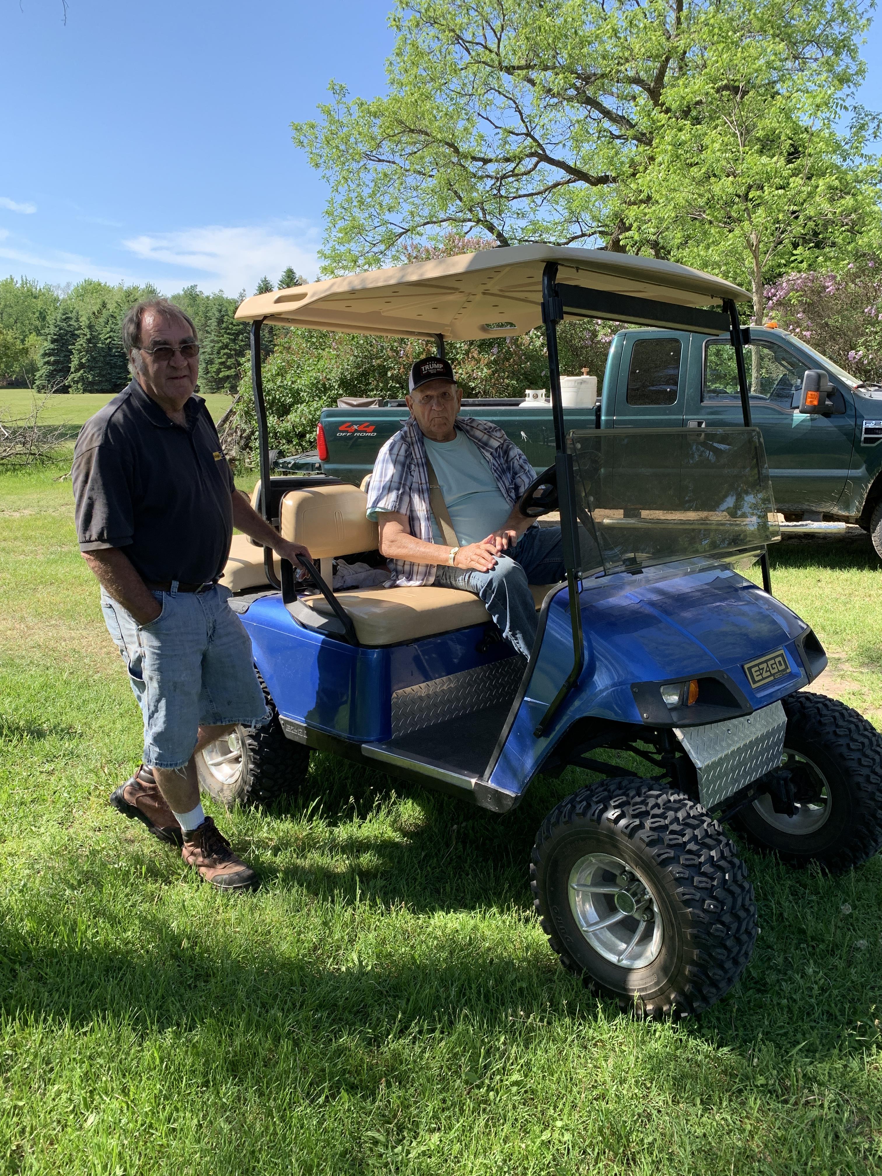 Two men standing next to a golf cart