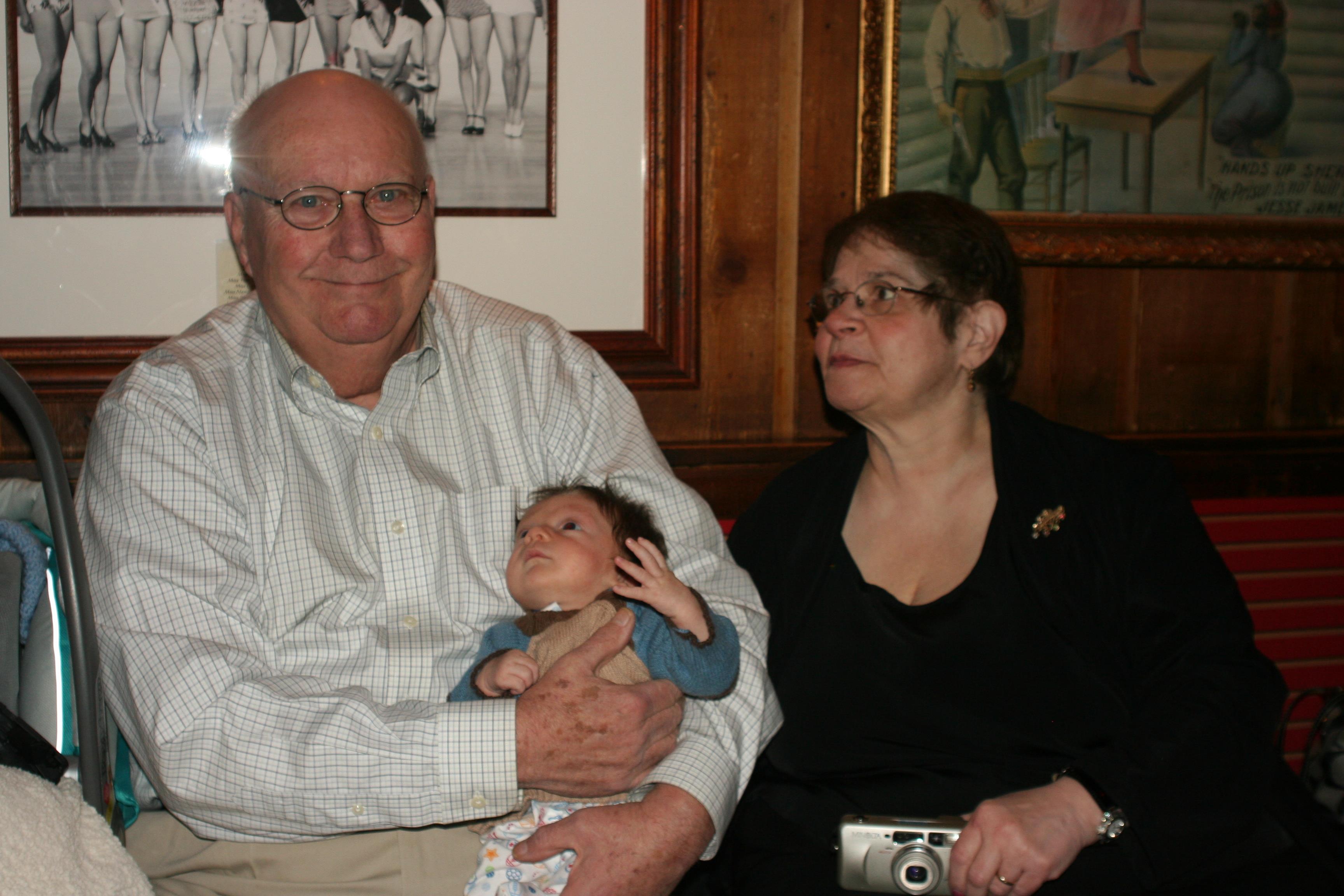 A man and woman sitting on a couch holding a baby