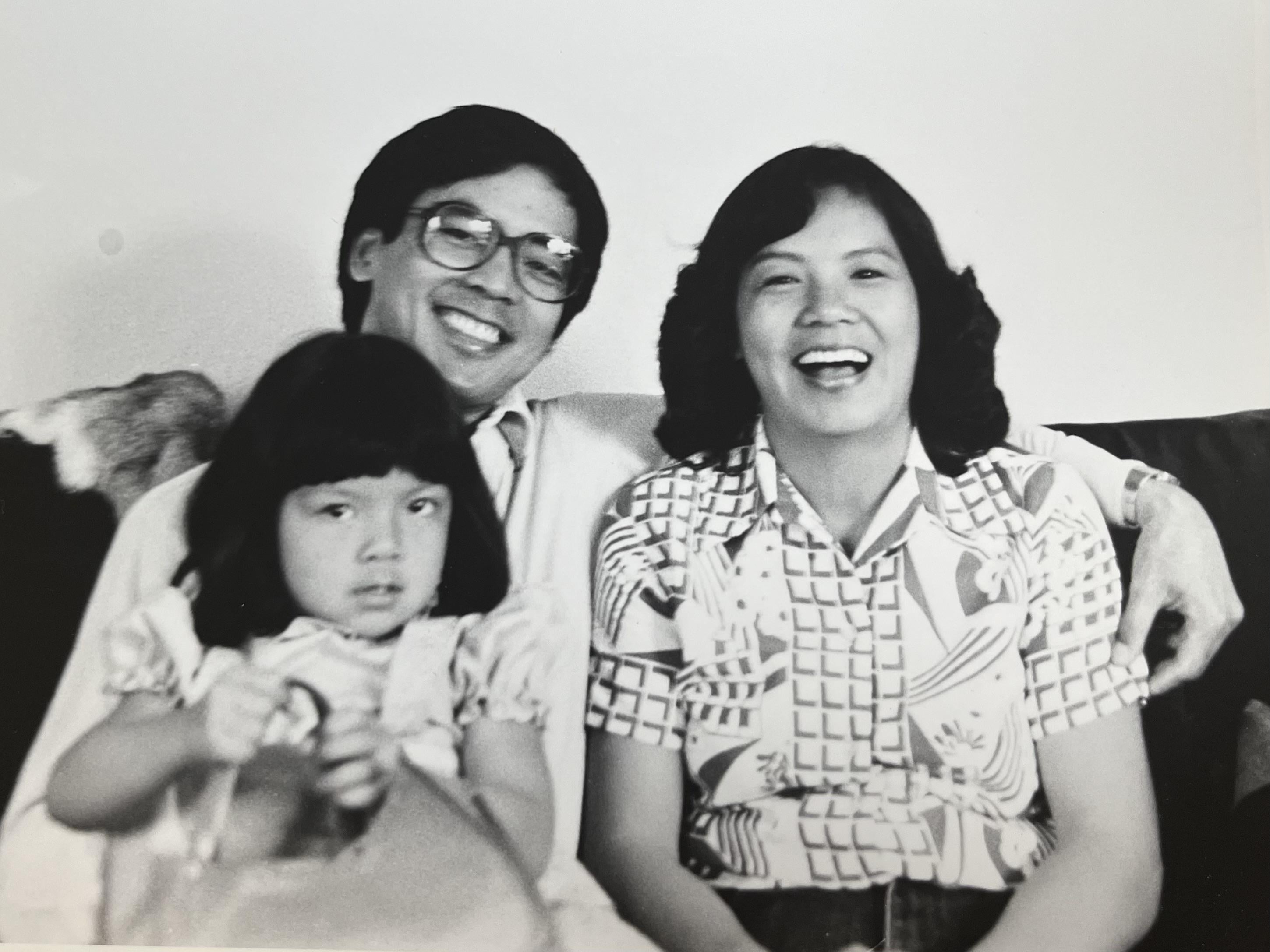 A man and woman sitting on a couch with a baby