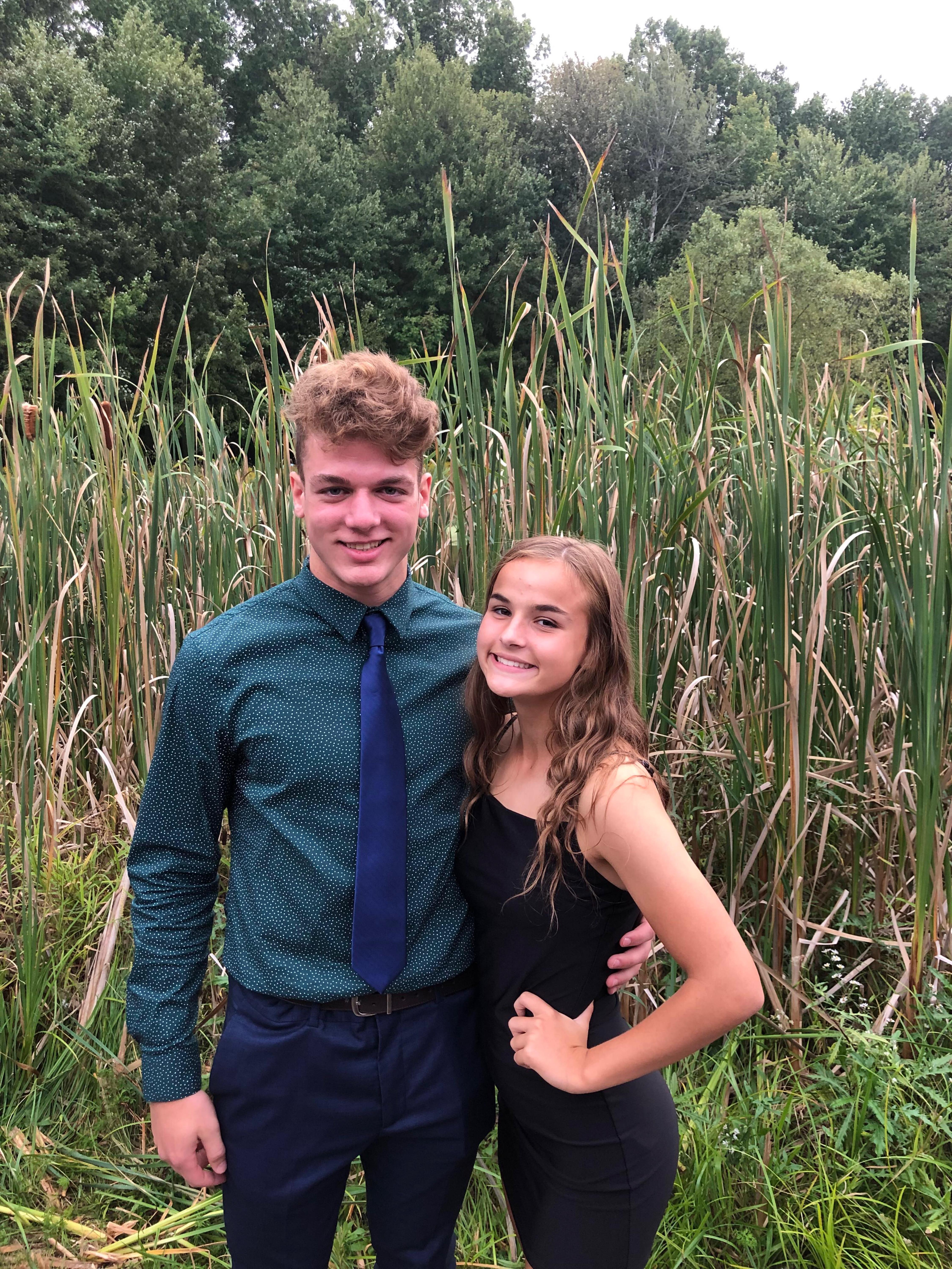 A man and woman standing in front of tall grass
