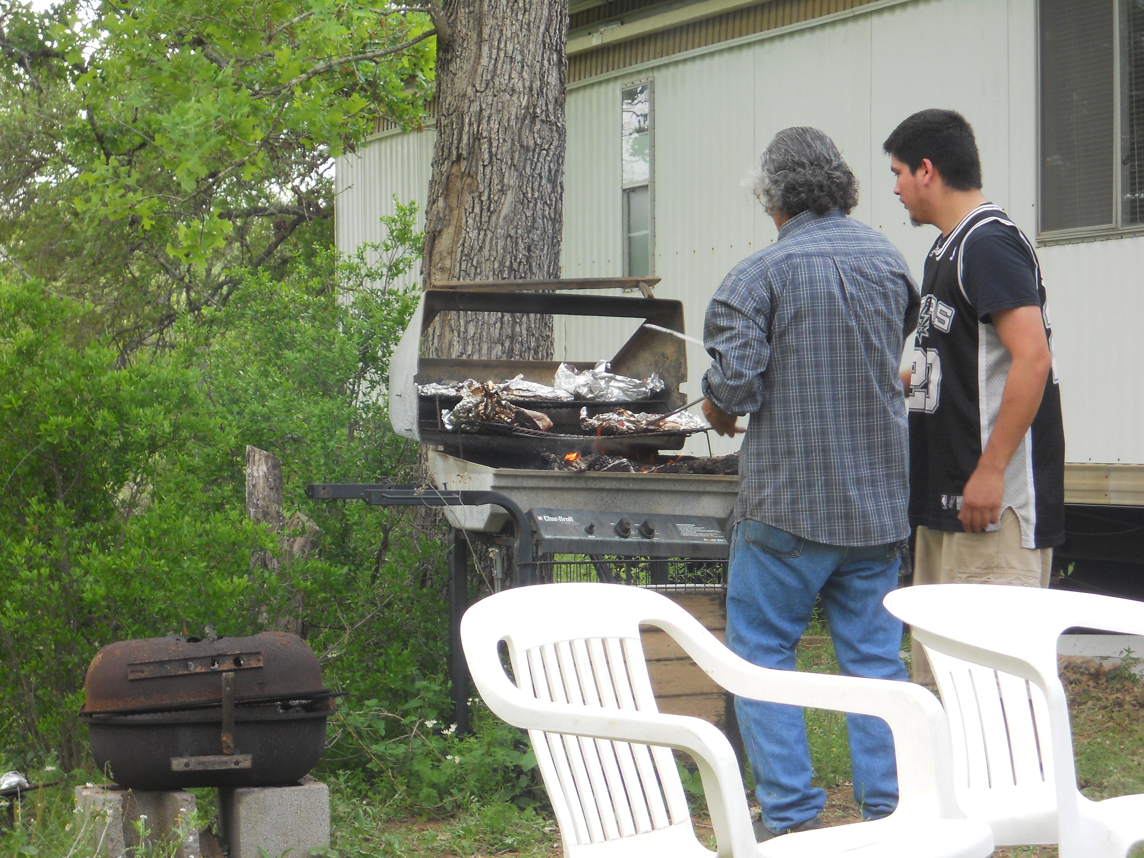 A couple of men grilling fish