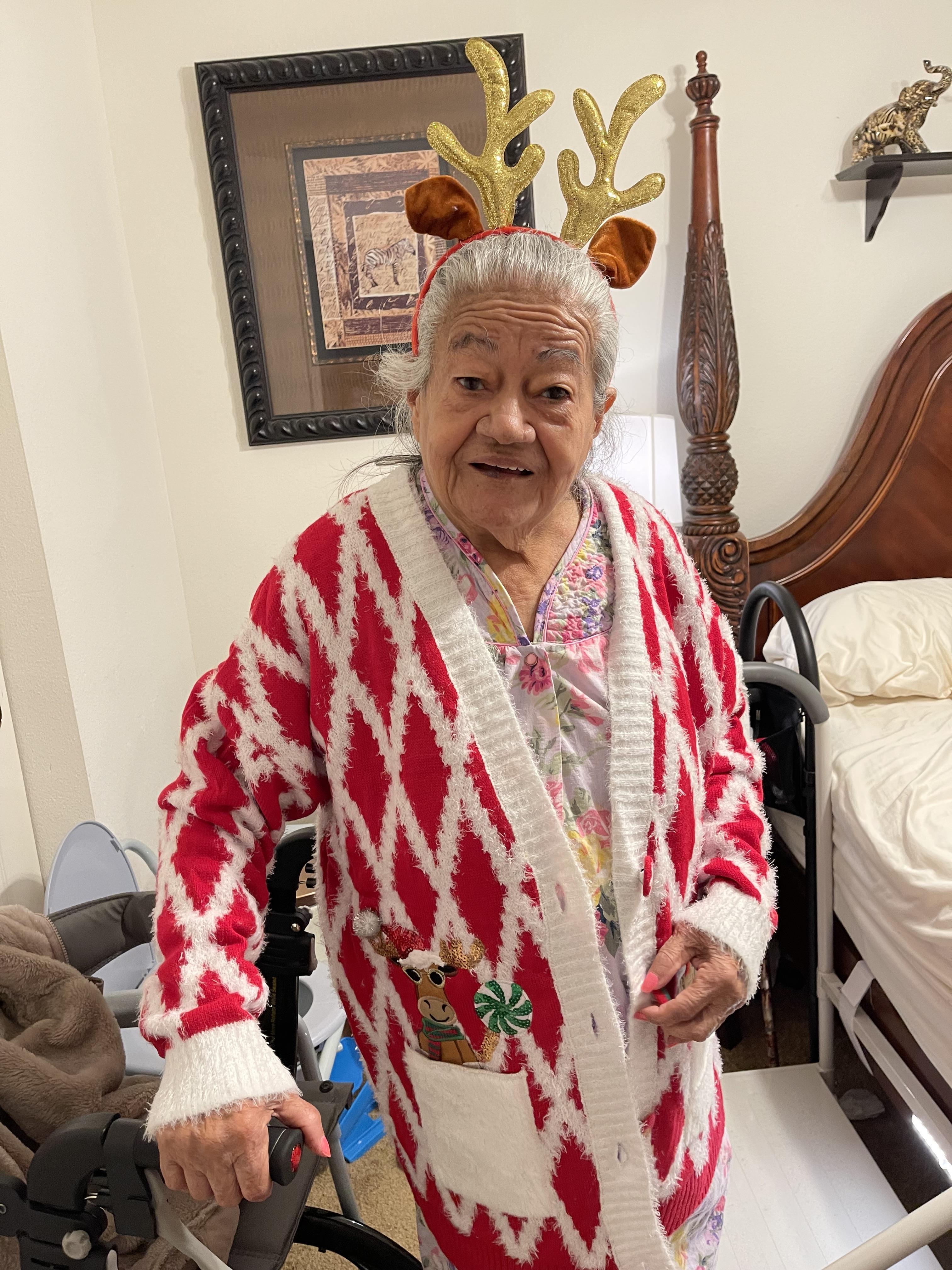 An old woman wearing a red and white sweater and reindeer antlers