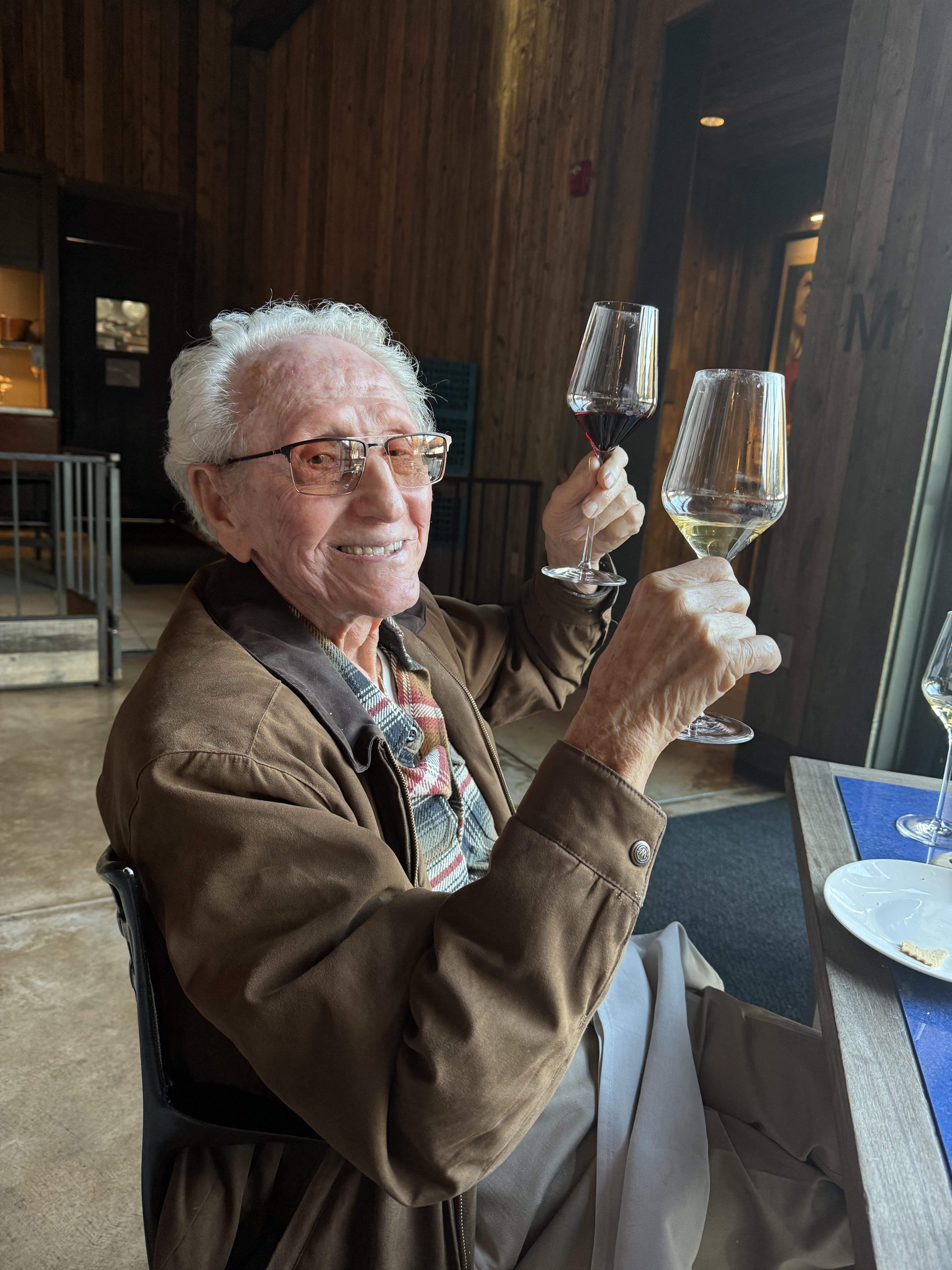 A man sitting at a table holding wine glasses