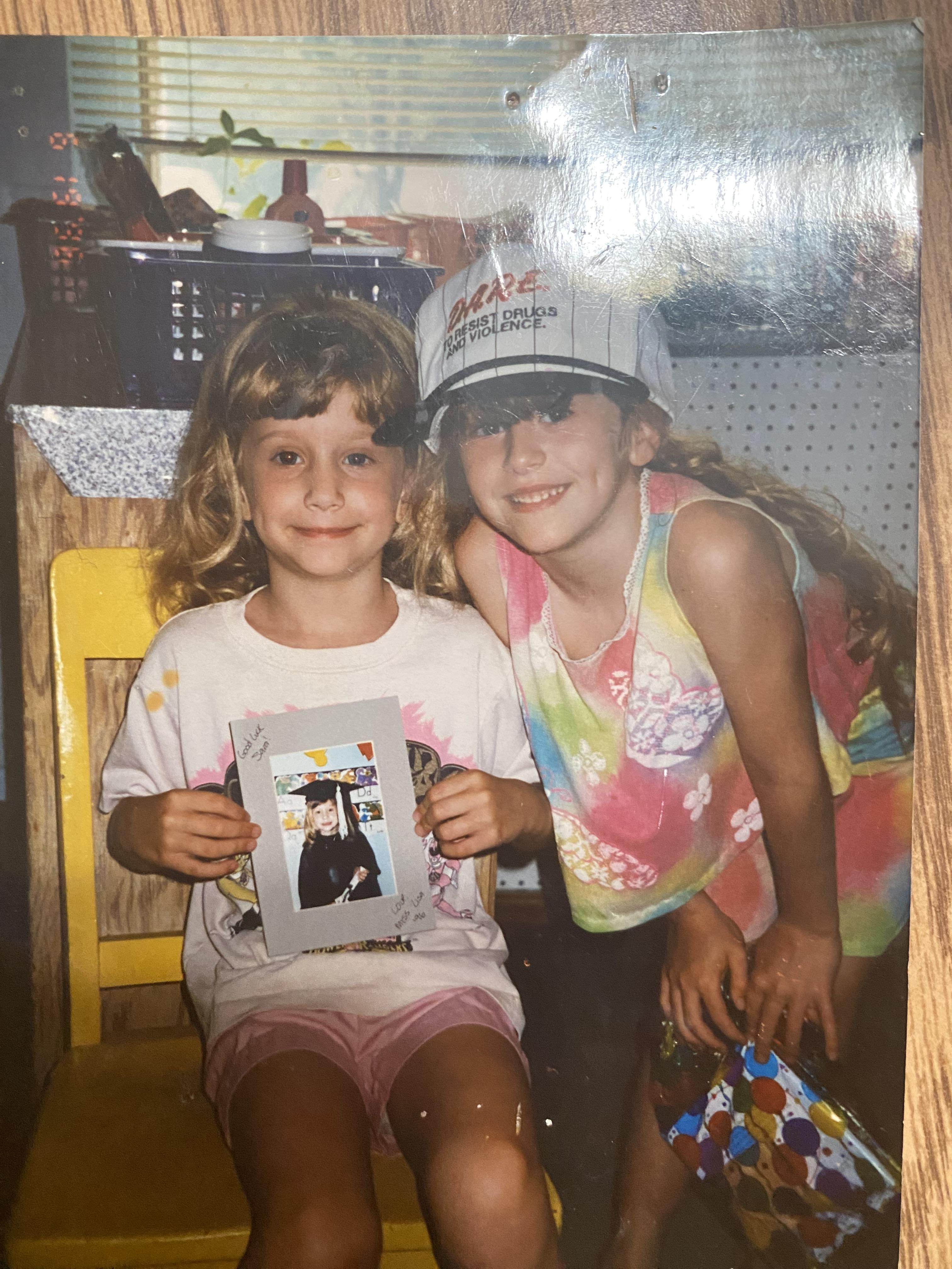 A couple of girls sitting on a chair holding a picture