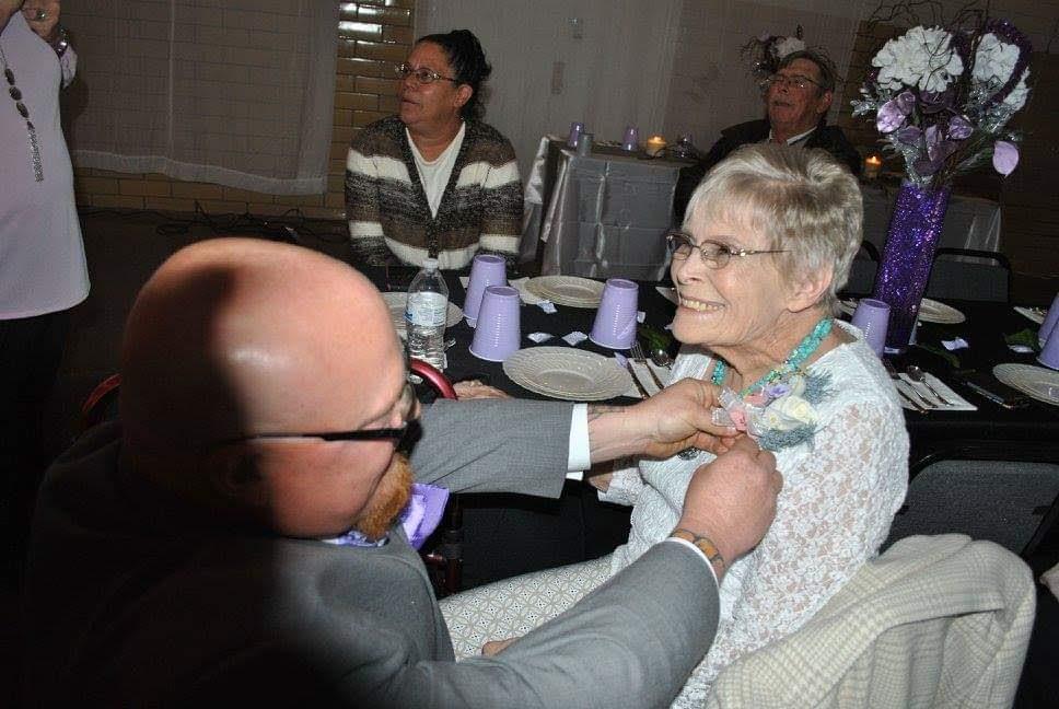 A man putting a necklace on a woman's neck