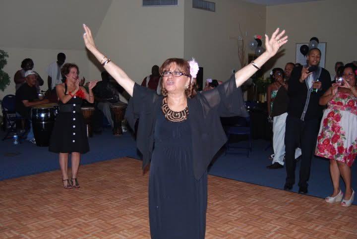 A woman in a black dress with her arms up