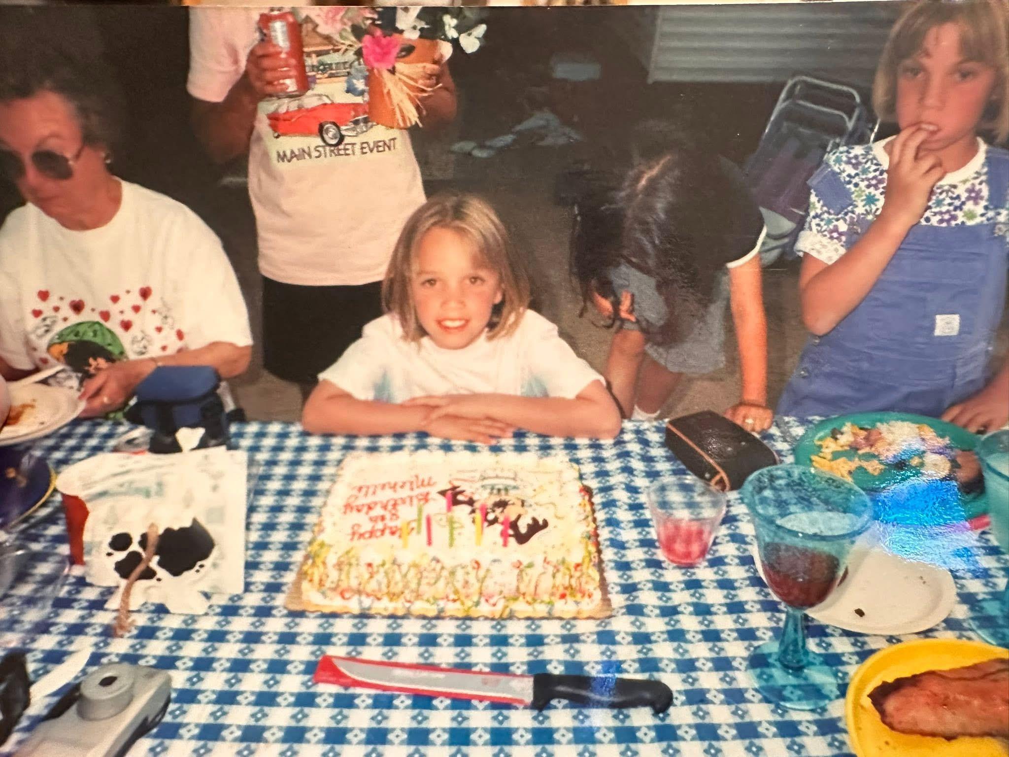 A group of people around a table with a cake