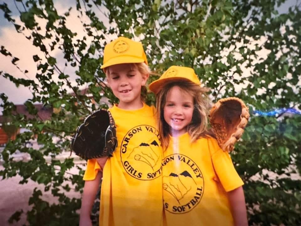 A boy and girl wearing baseball uniforms and gloves