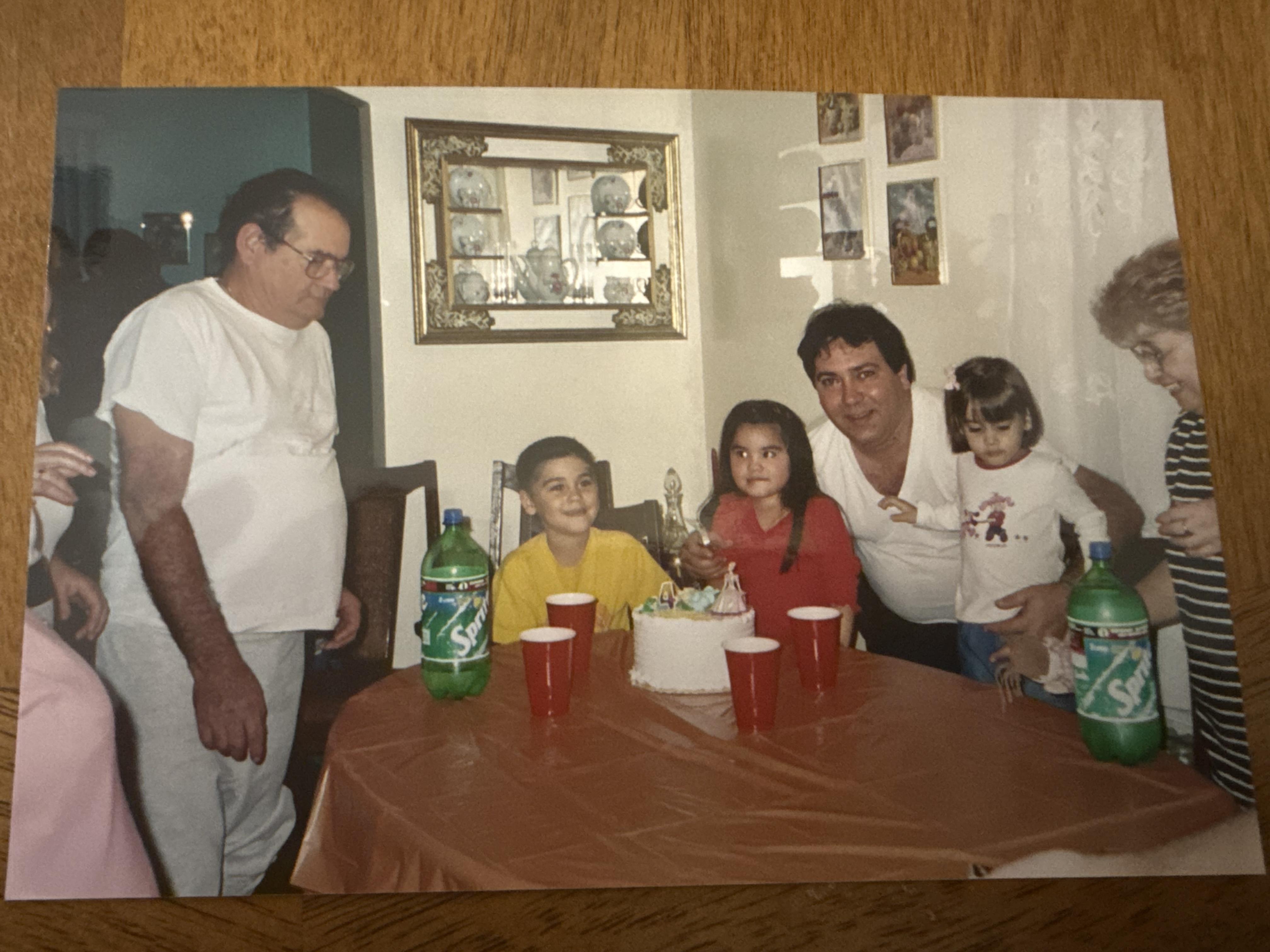 A group of people around a table with a cake