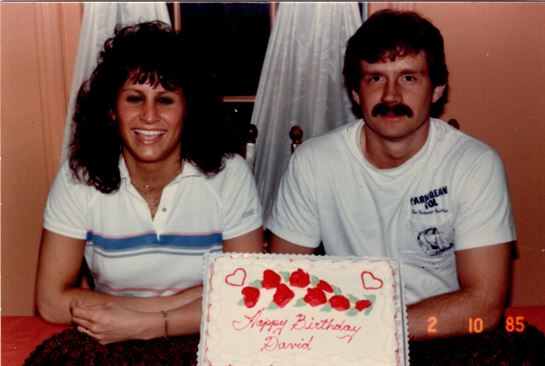 A man and woman sitting next to a cake