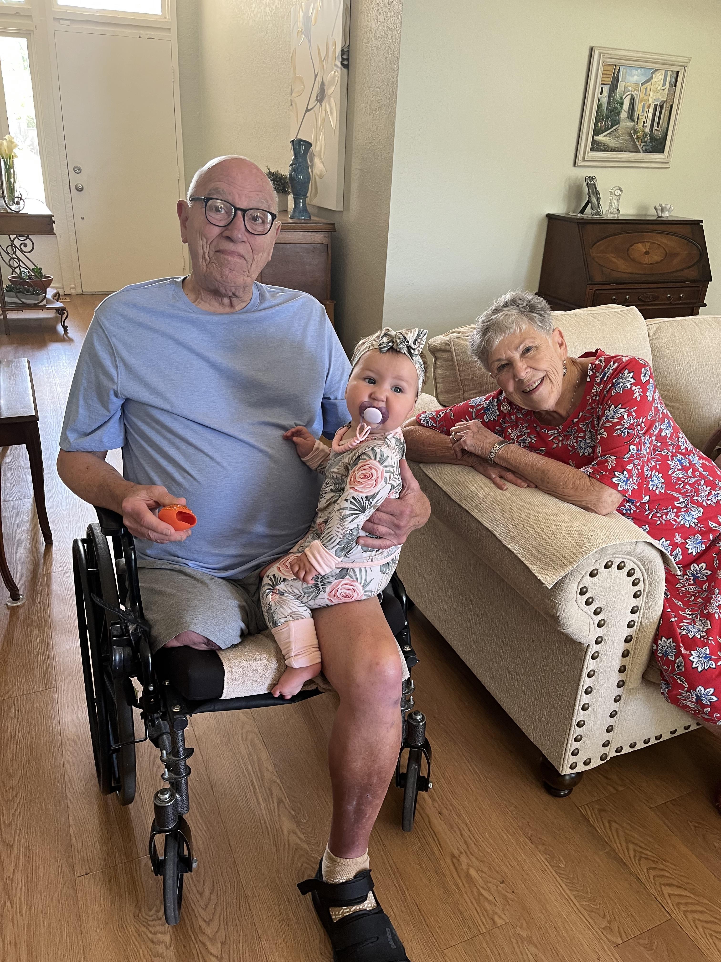 A man and woman sitting in a wheelchair with a baby