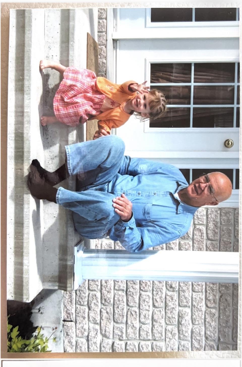 A man and a child sitting on a stone ledge