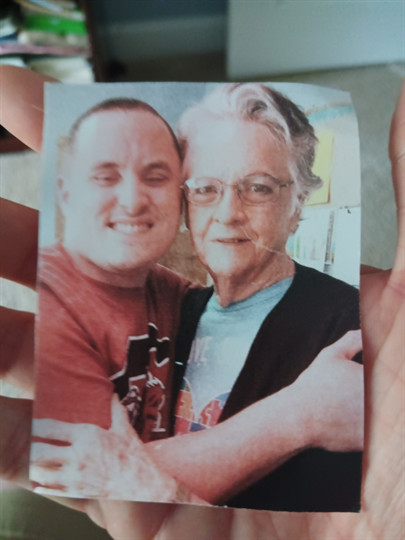 A hand holding a photo of a man and woman