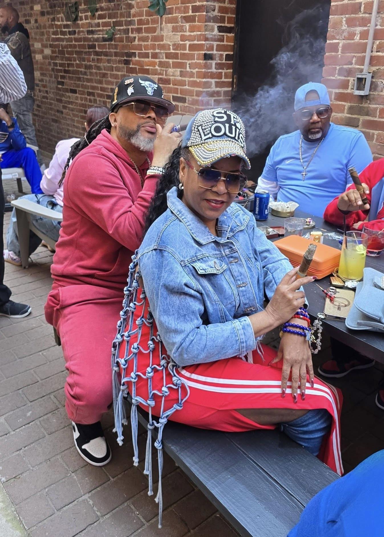 A man and woman sitting at a table with smoking cigars