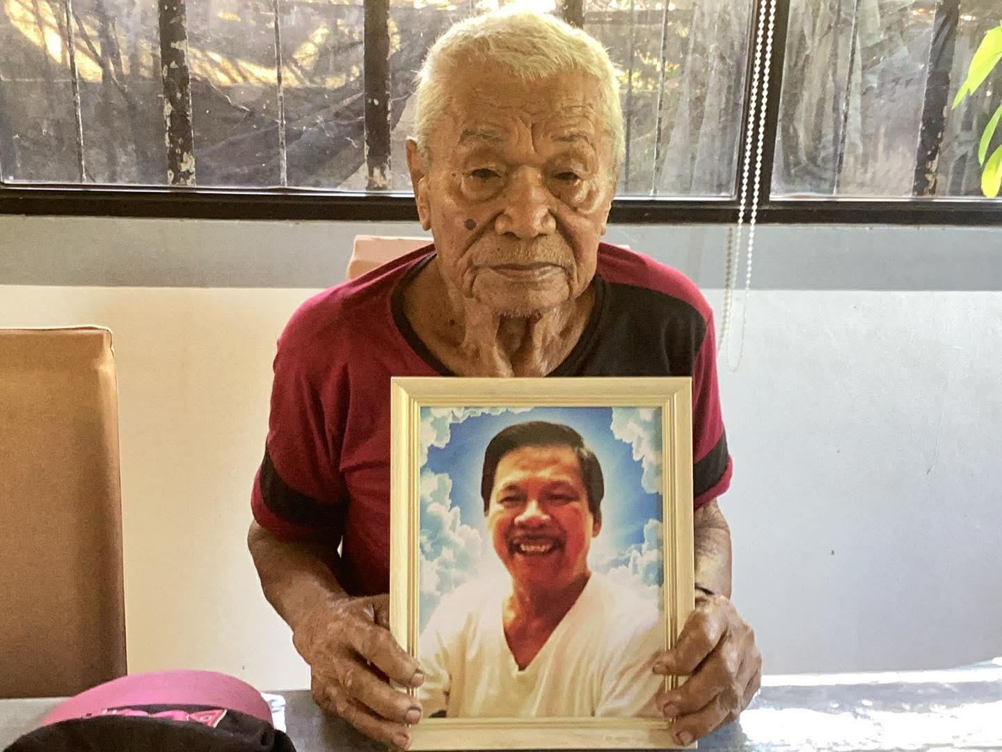 An old man holding a picture of a man