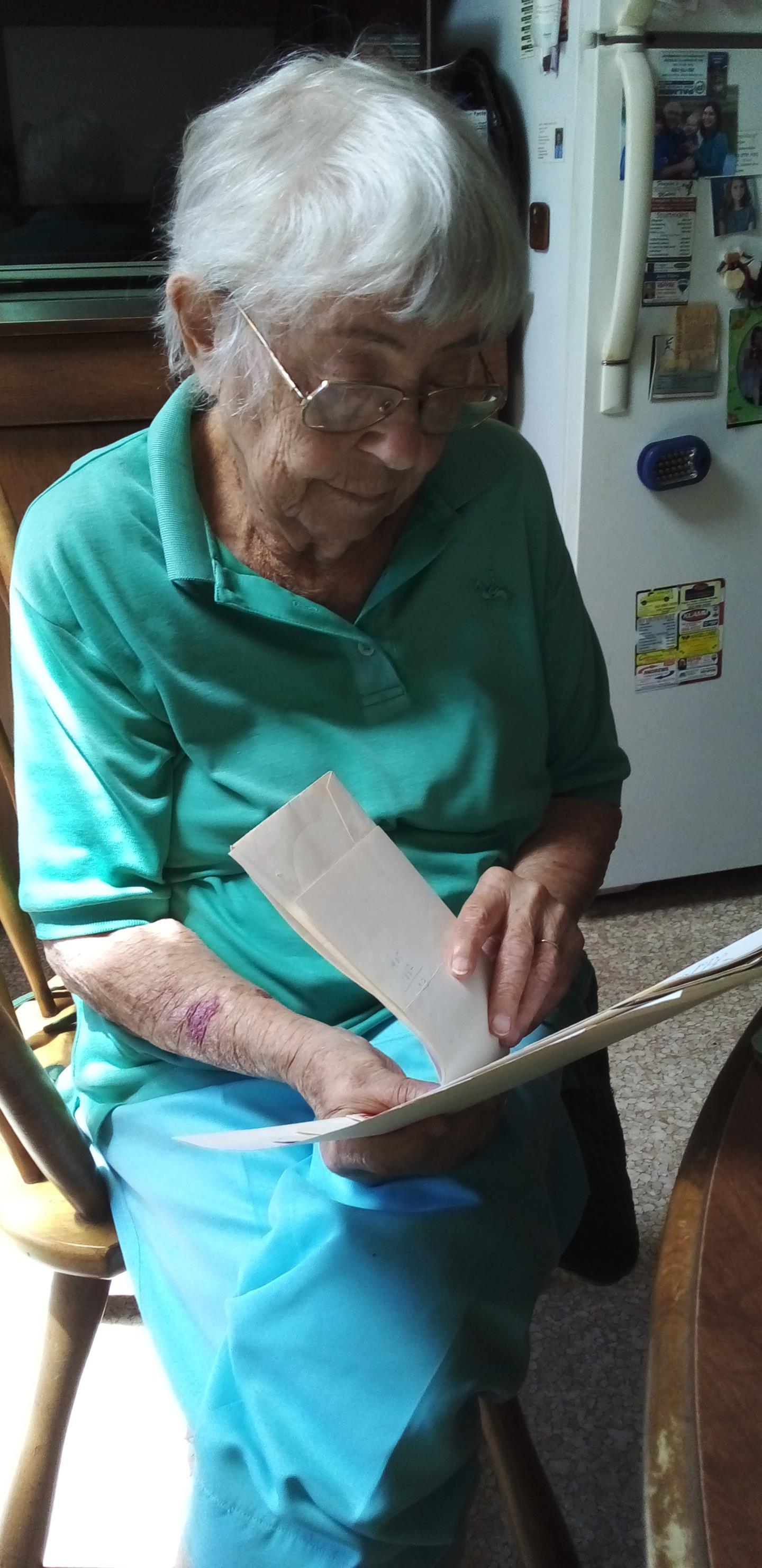 An old woman sitting in a chair reading a paper