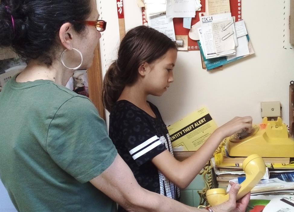 A woman and a girl using a yellow telephone