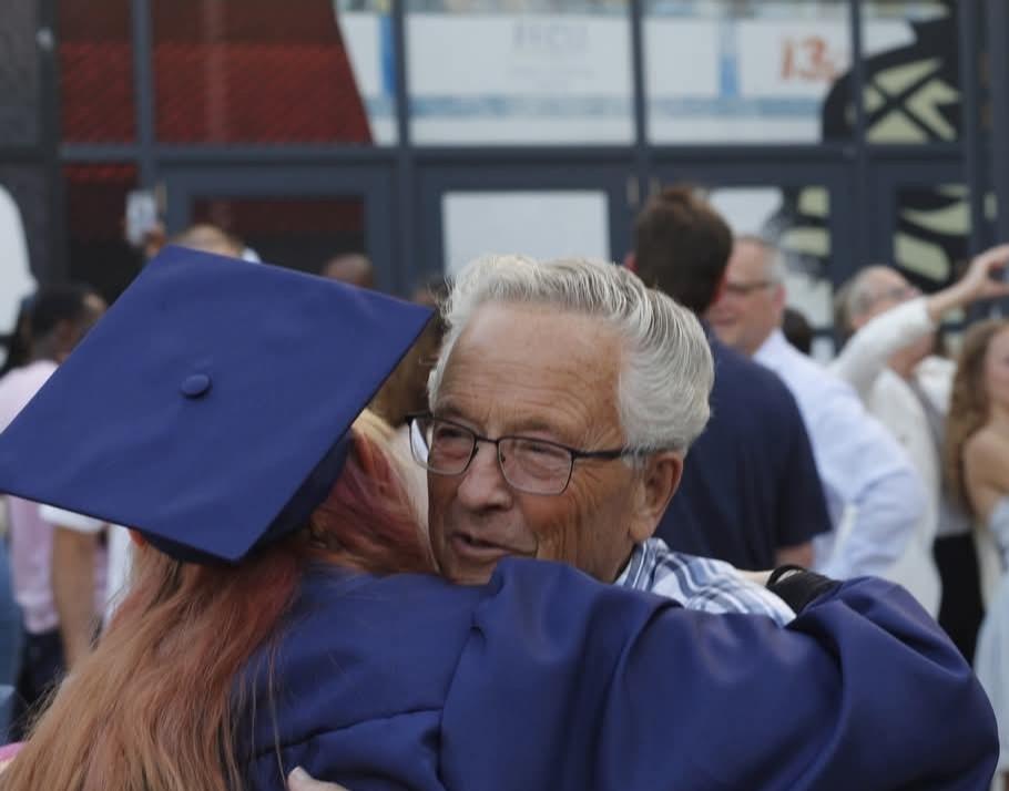 A man in a graduation cap hugging a woman
