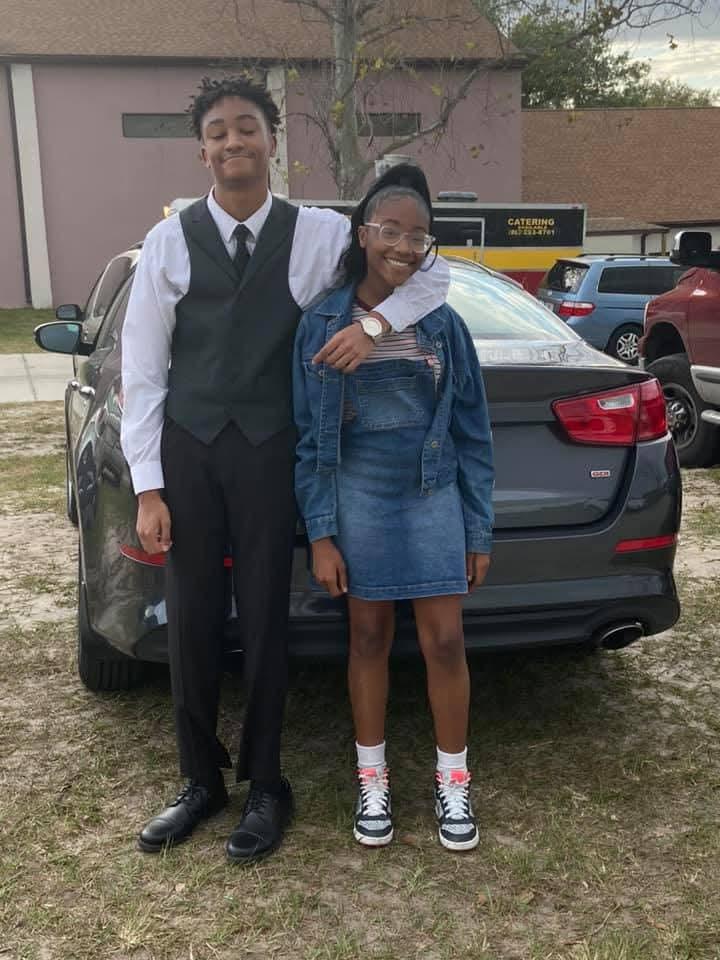 A boy and girl standing next to a car