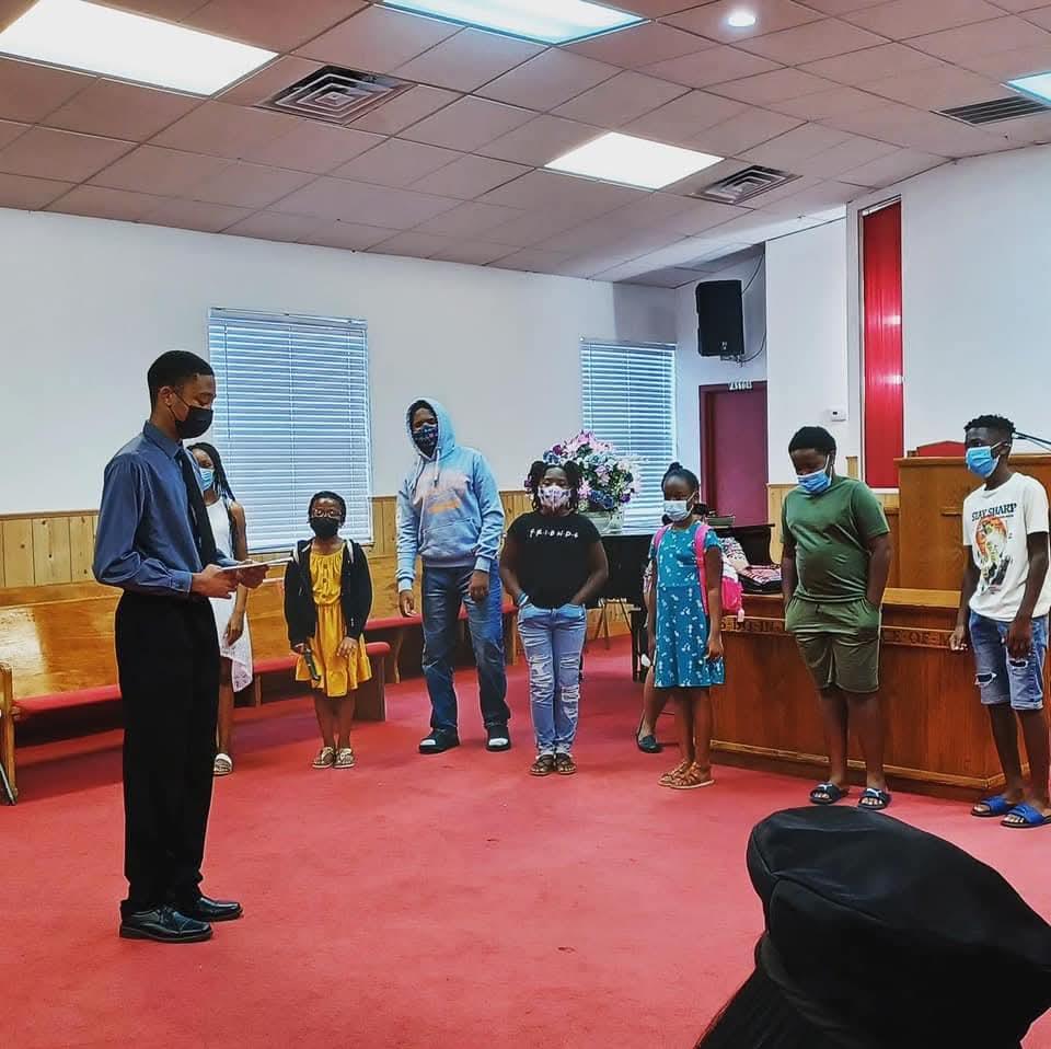 A group of people standing in a room with a man standing in front of him
