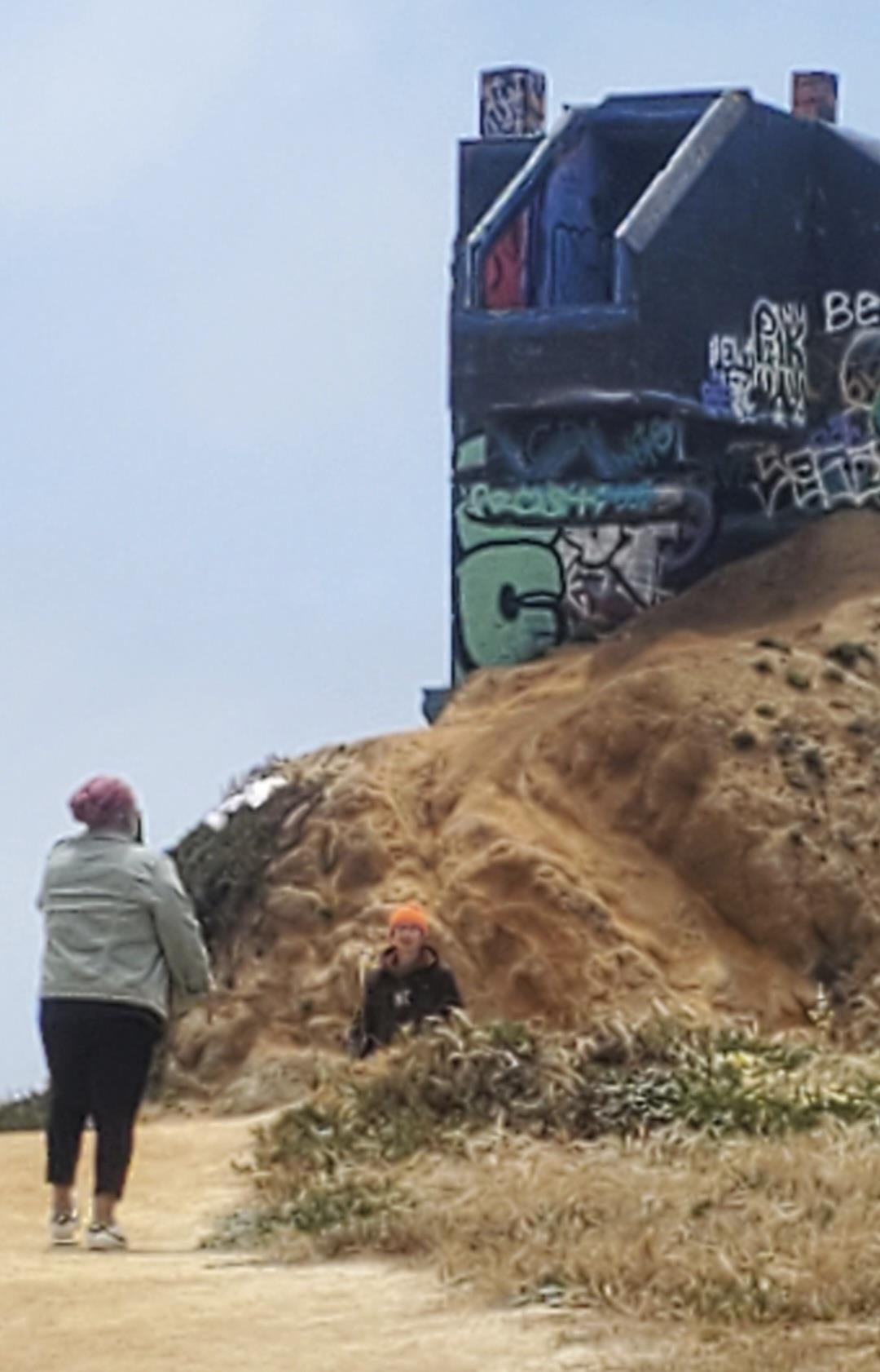 A woman and child on a hill with graffiti on the side