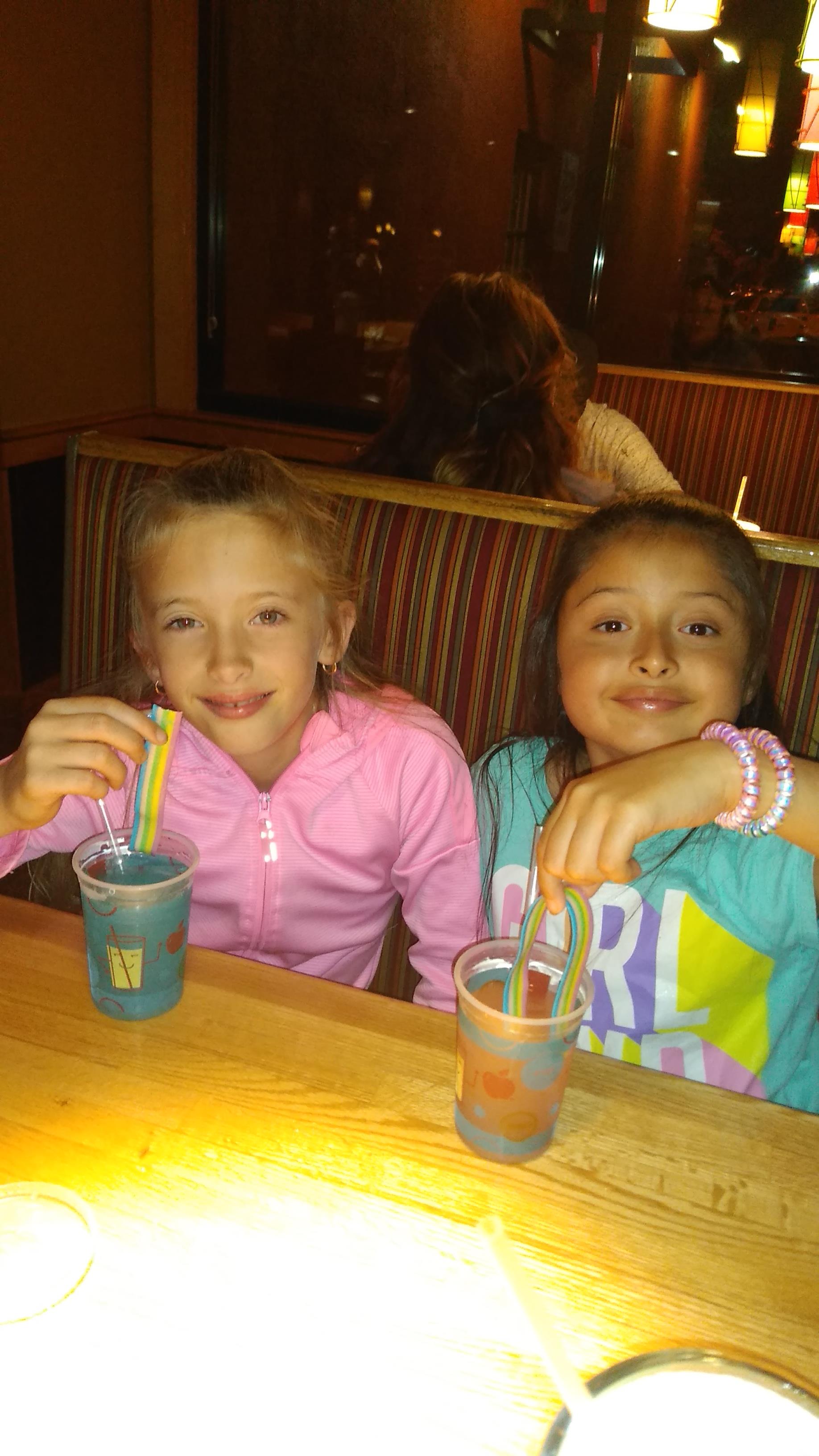 Two girls sitting at a table drinking from cups