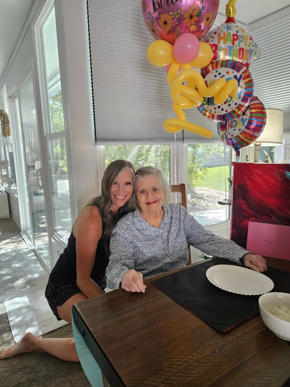 A woman sitting at a table with a woman smiling
