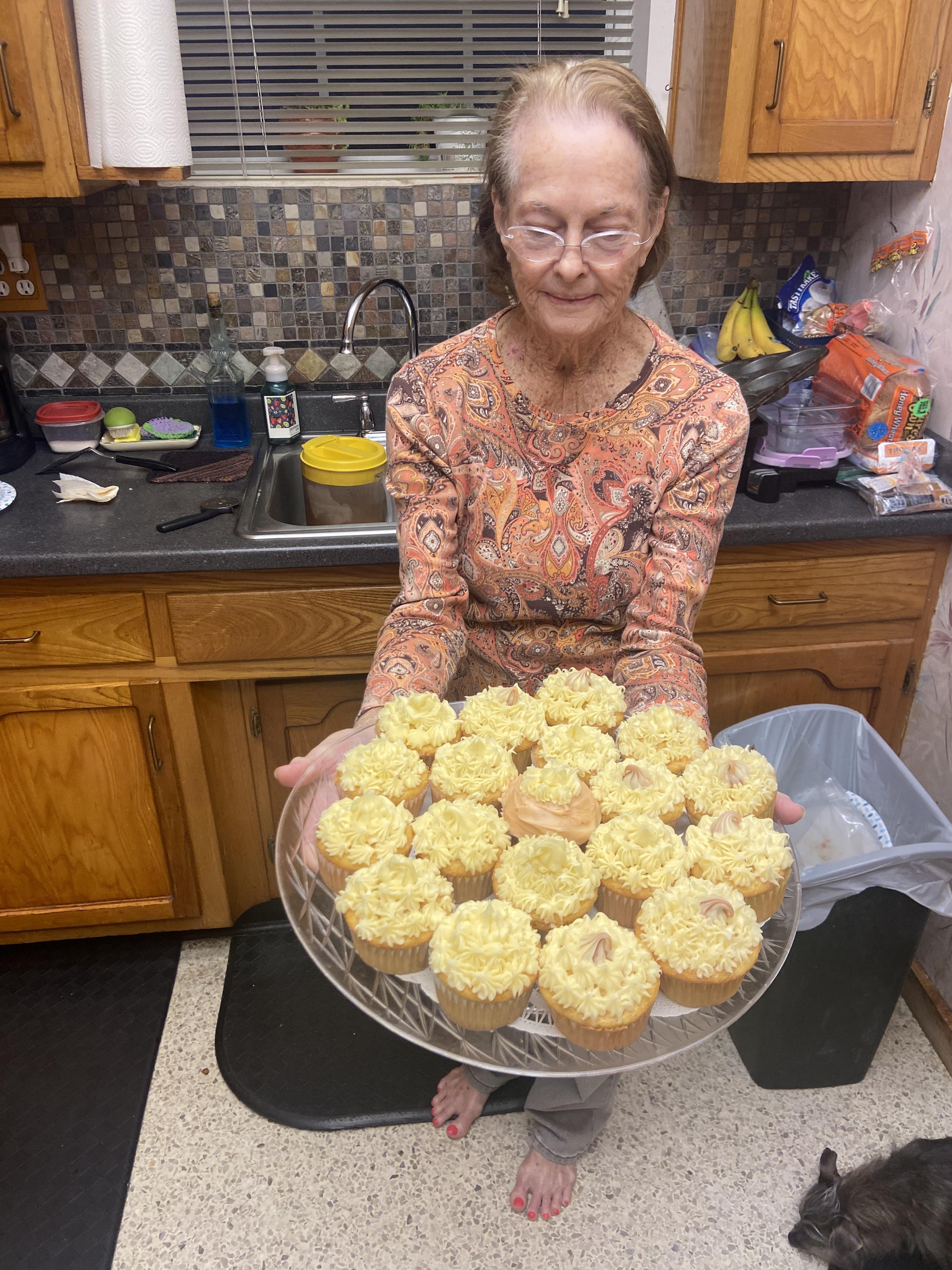 A woman holding a plate of cupcakes