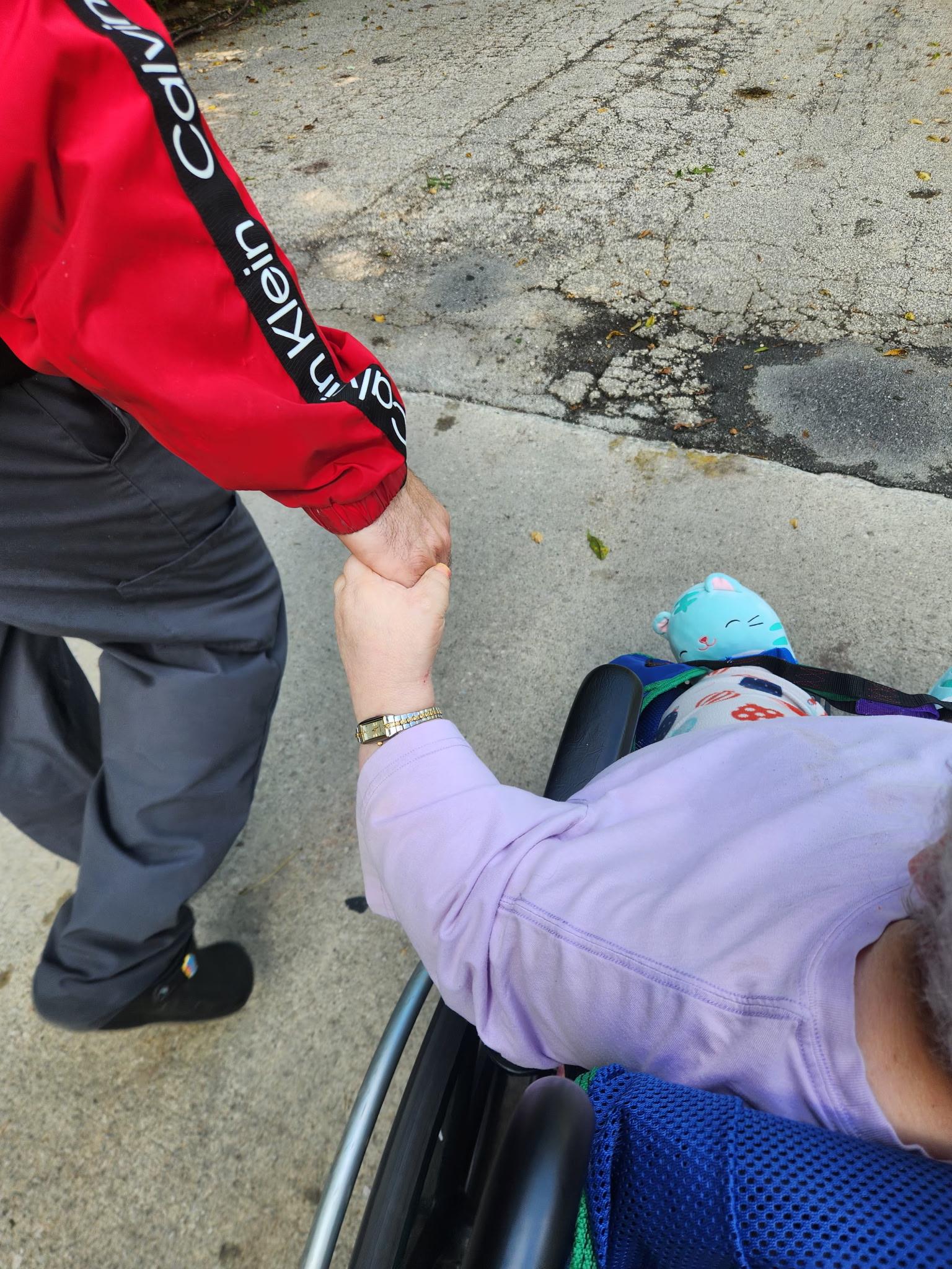 A person in a wheelchair holding hands