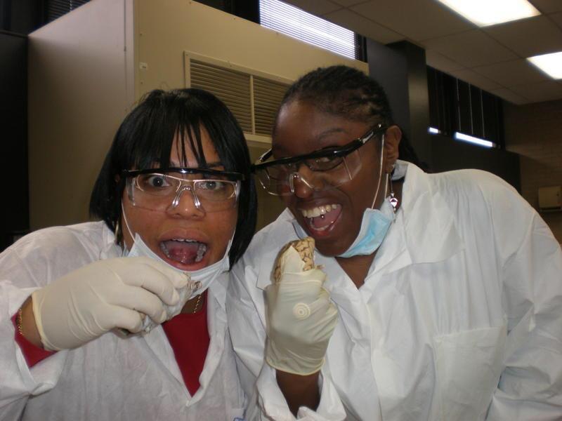 A couple of women wearing white lab coats and gloves