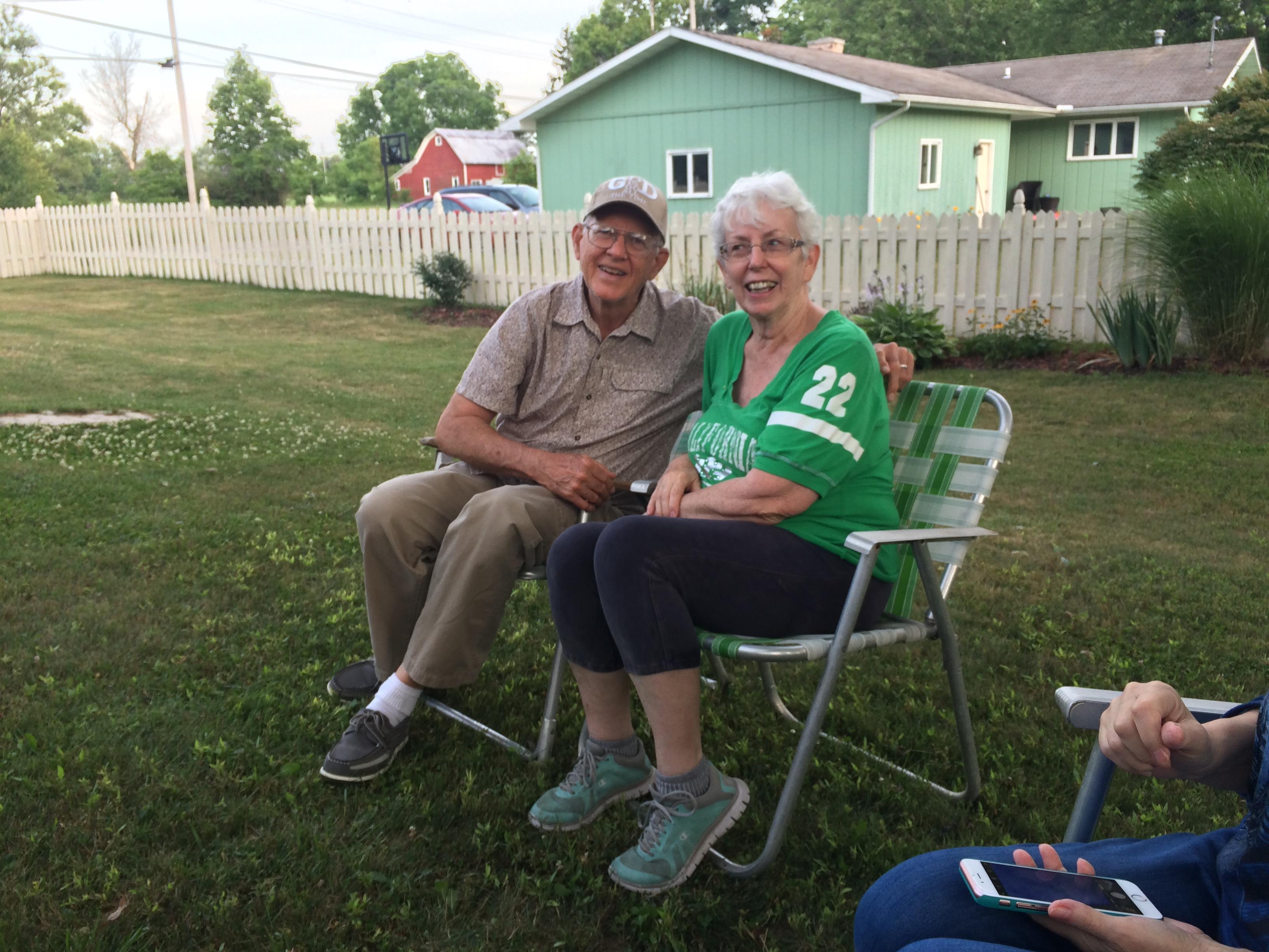 A man and woman sitting in chairs in a yard