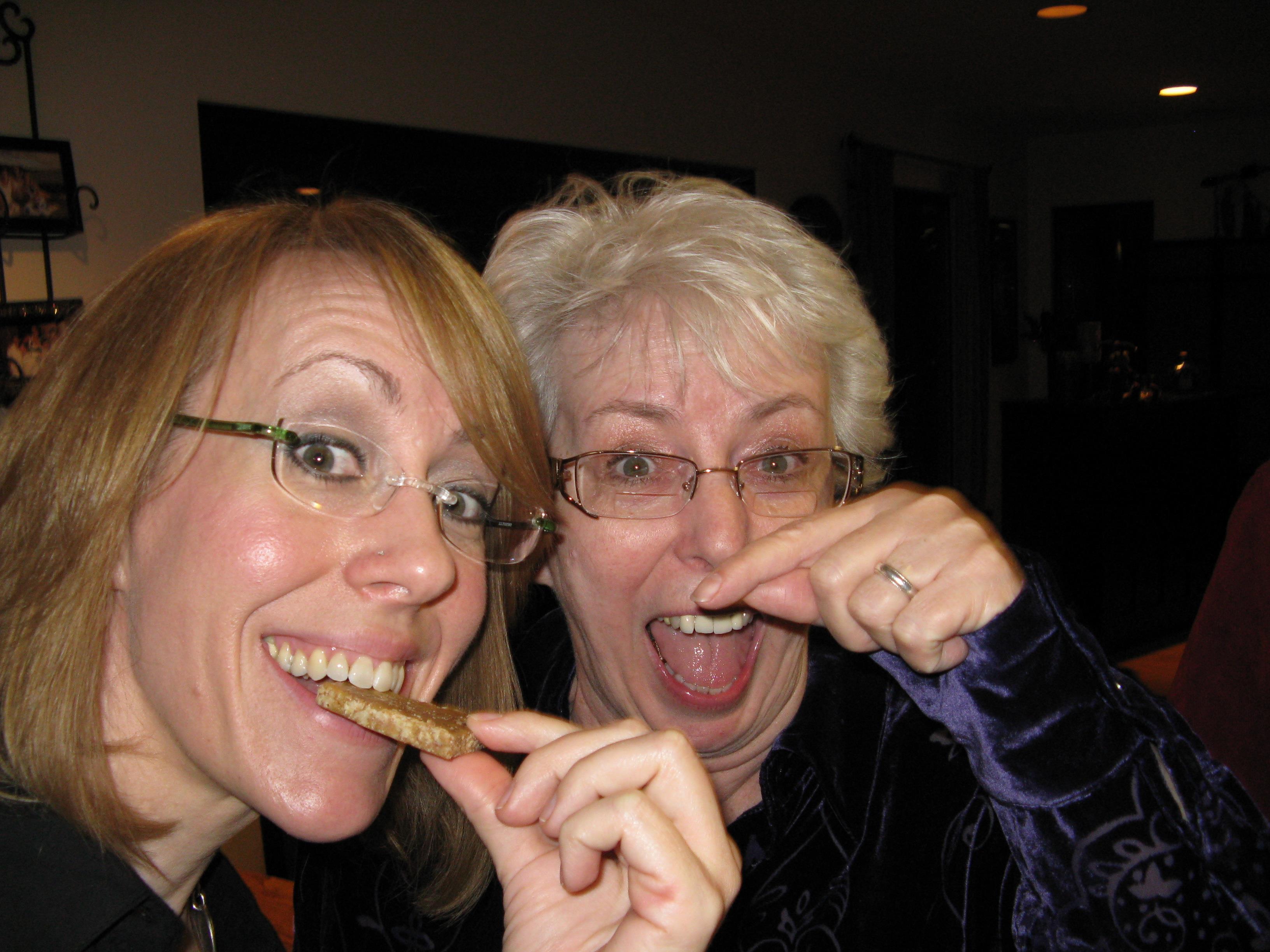 A couple of women eating a piece of food