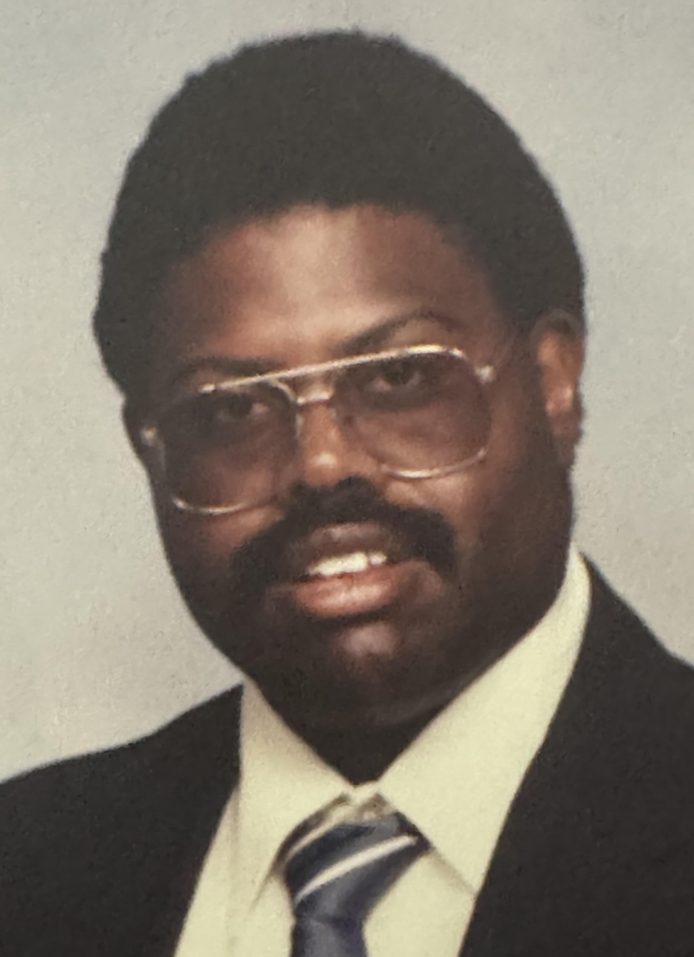 A man wearing glasses and a suit