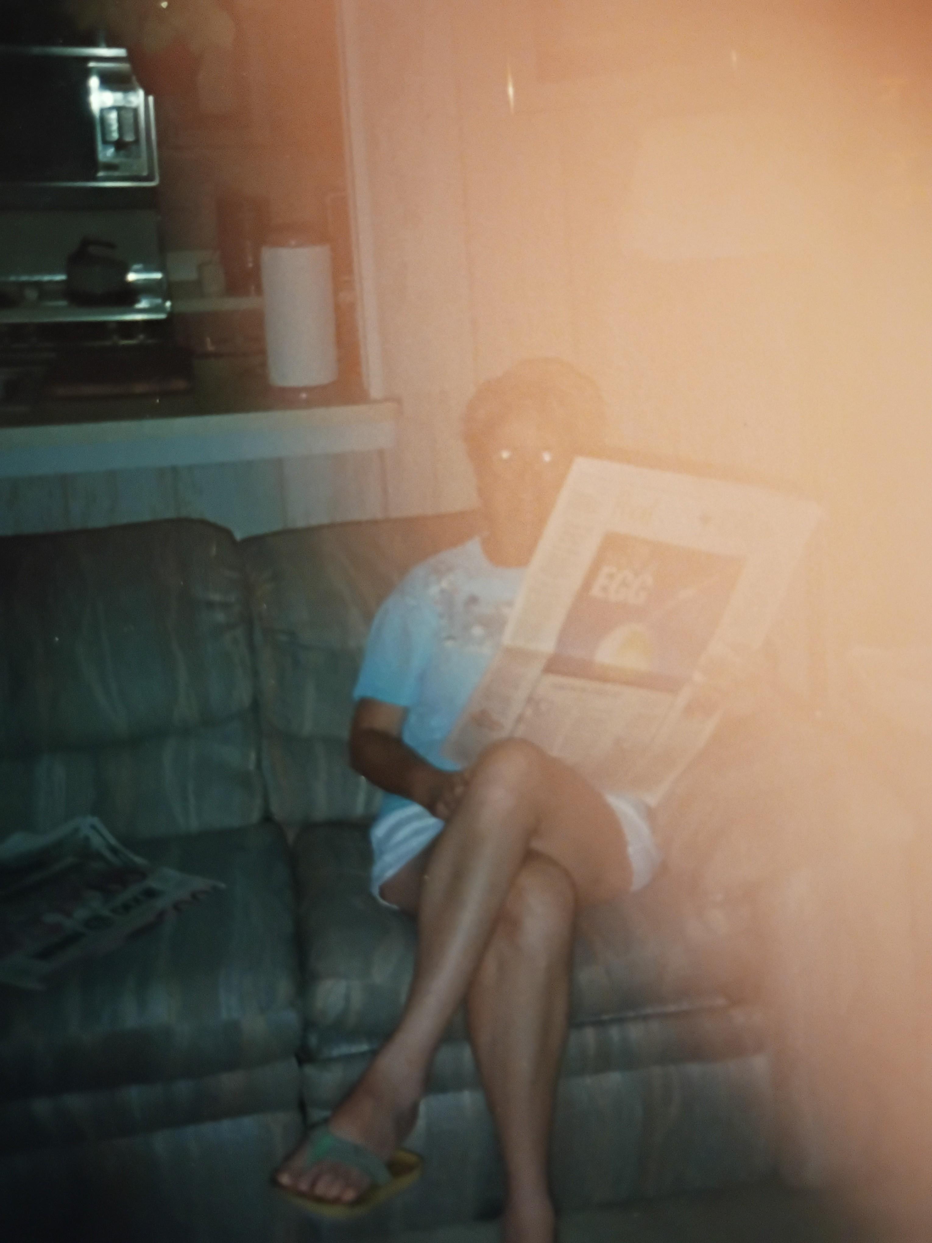 A person sitting on a couch reading a newspaper