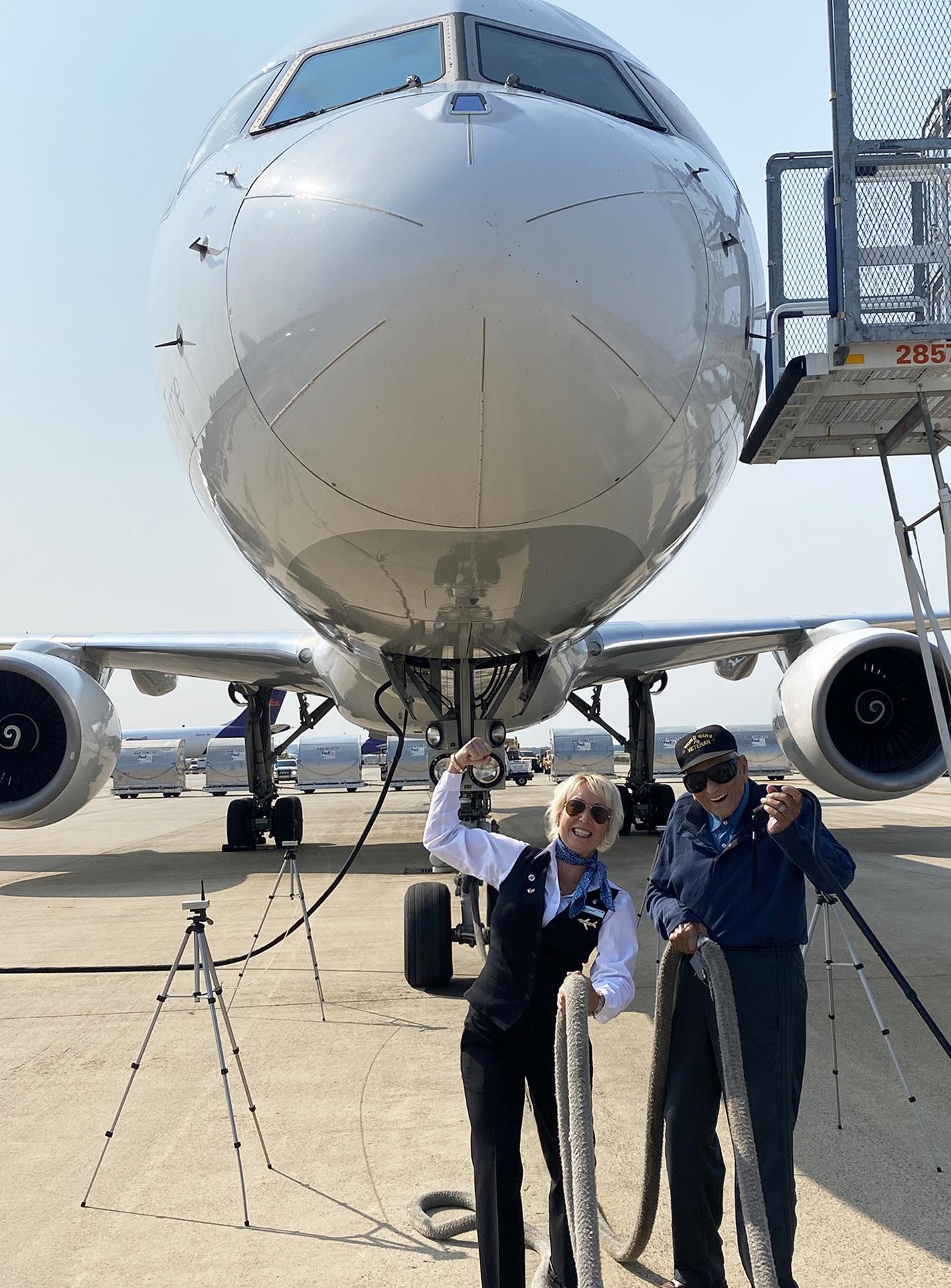 A man and woman standing next to a large airplane