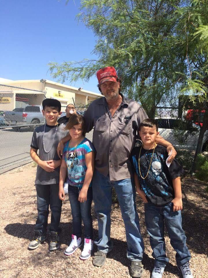 A man standing with his arms around a group of boys