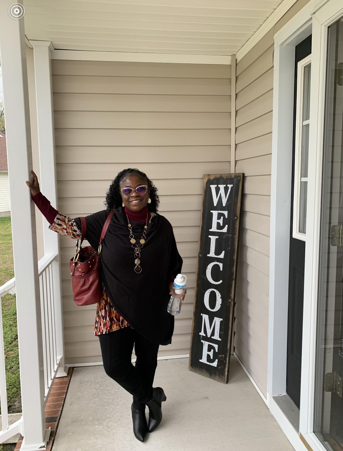 A woman standing in front of a welcome sign