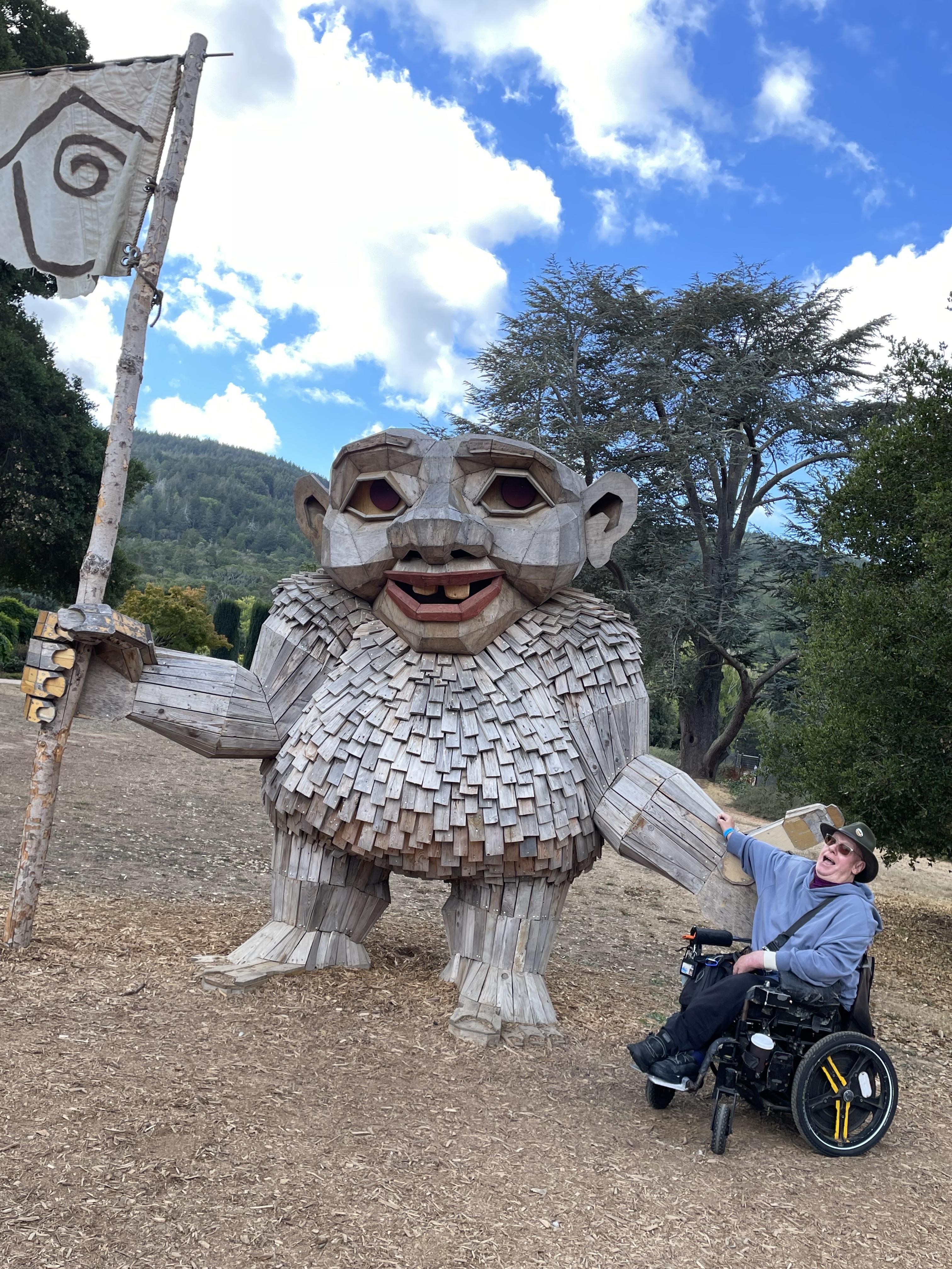 A man in a wheelchair holding a flag next to a large statue