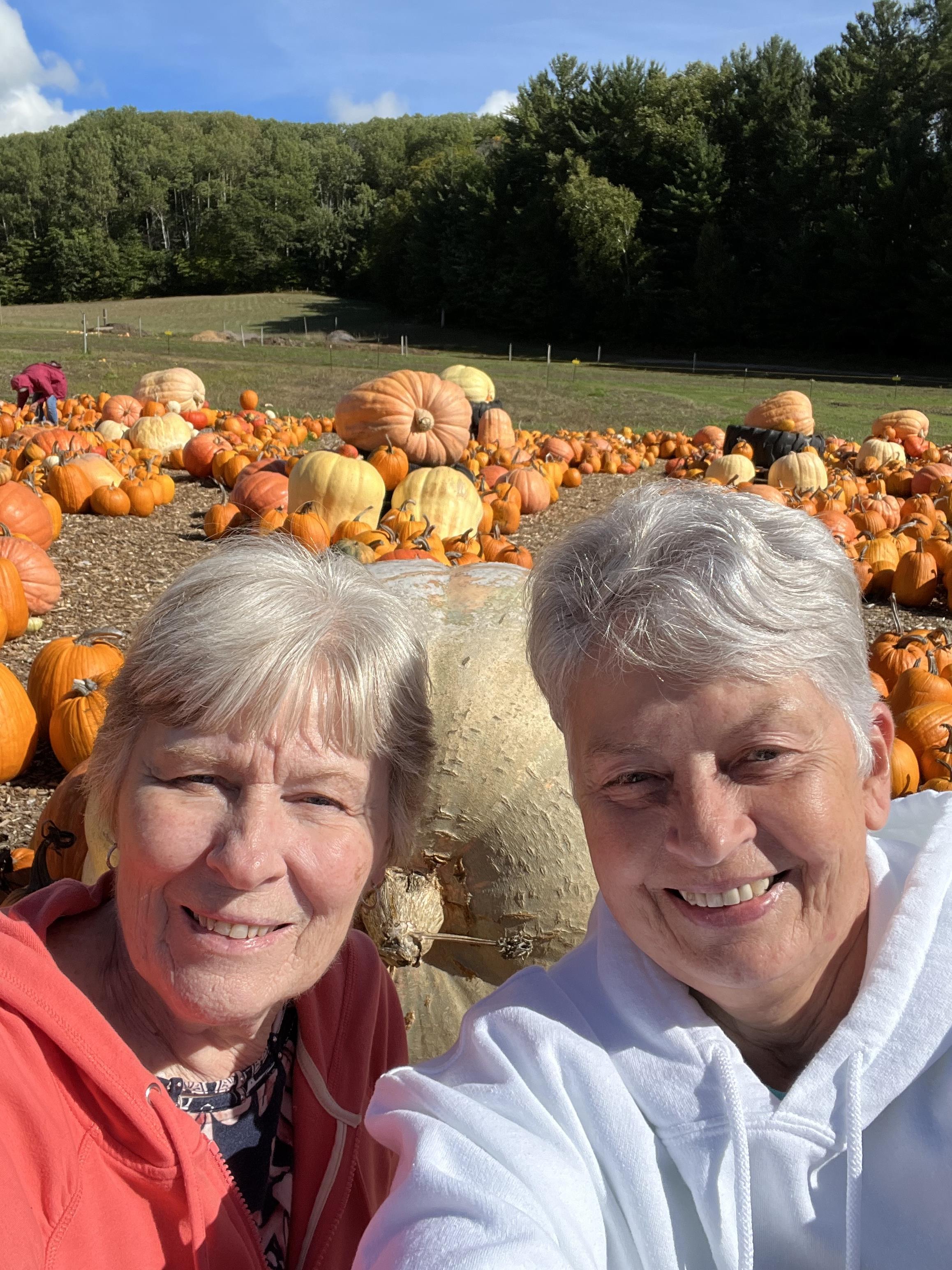 Two women taking a selfie in front of pumpkins