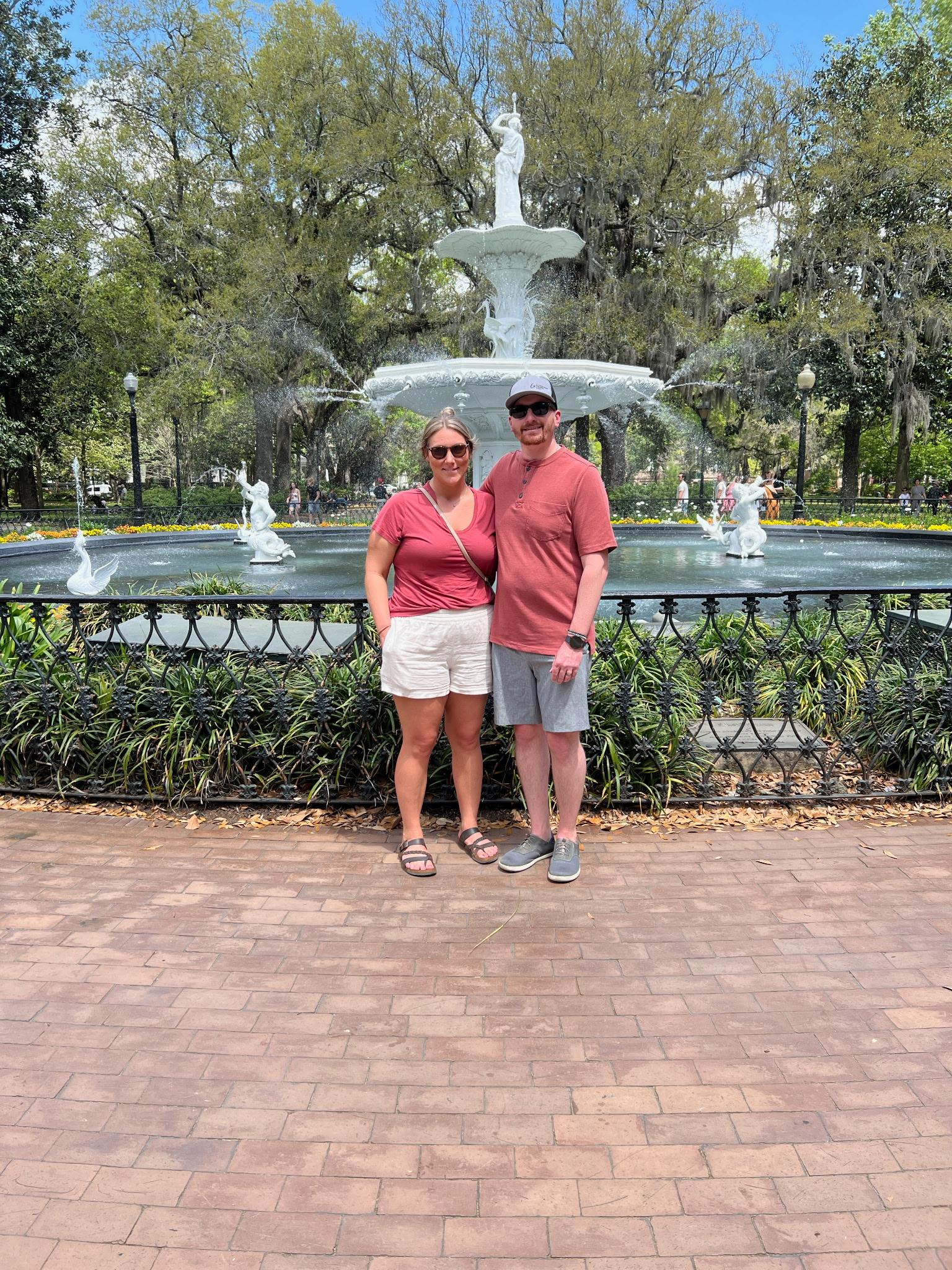 A man and woman standing in front of a fountain